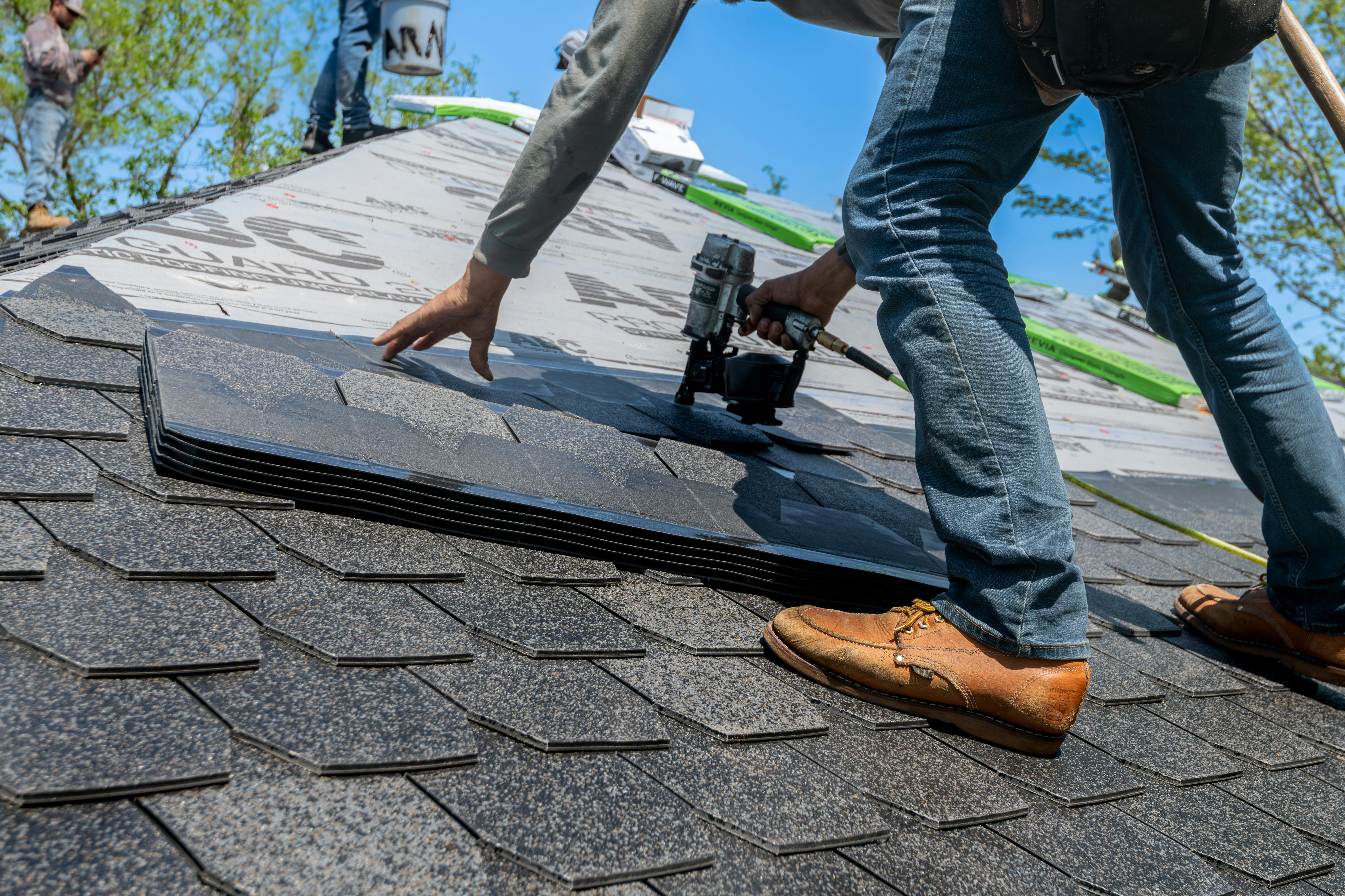 A man installing new shingles on a roof | Source: Pexels