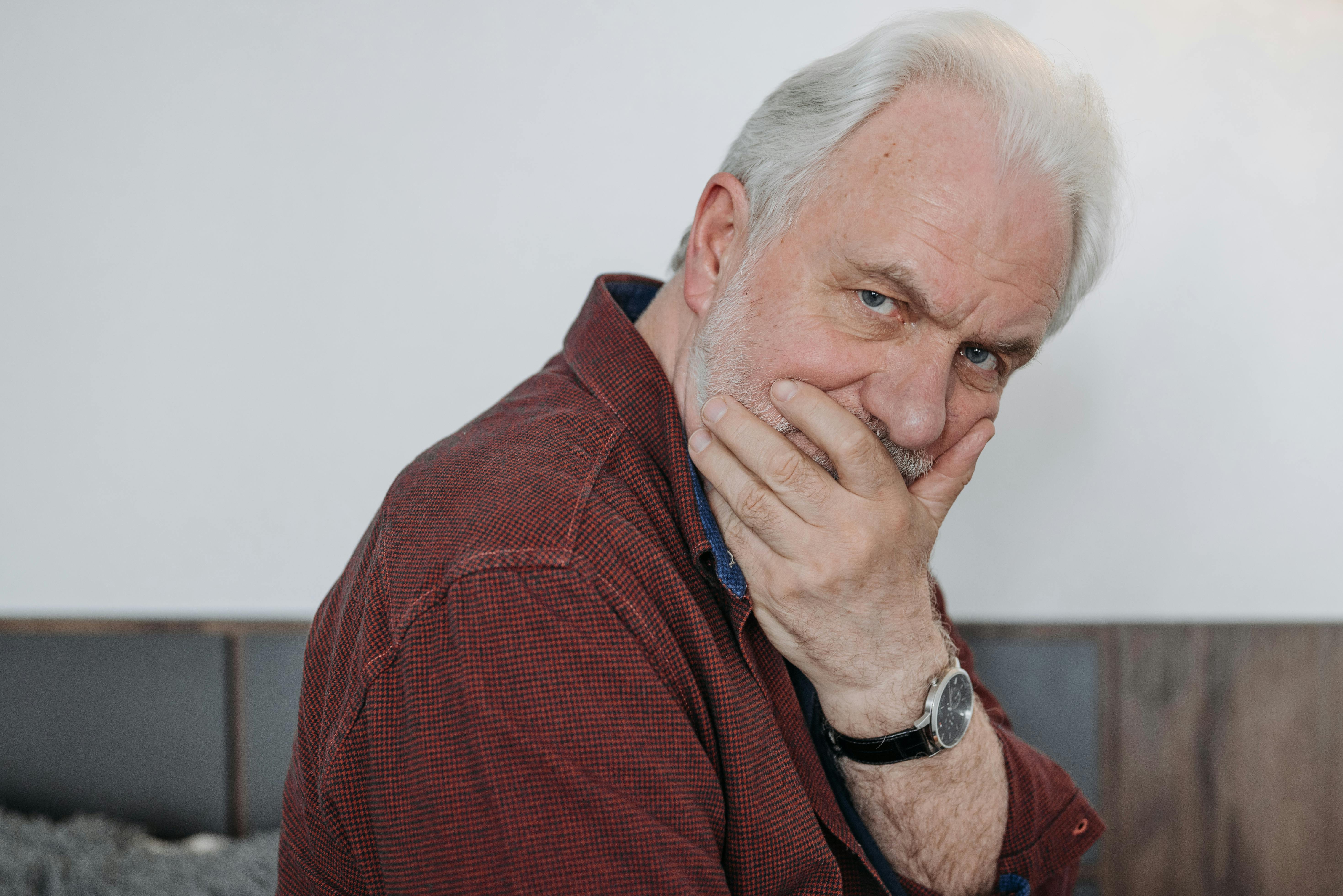 An older man covering his mouth | Source: Pexels