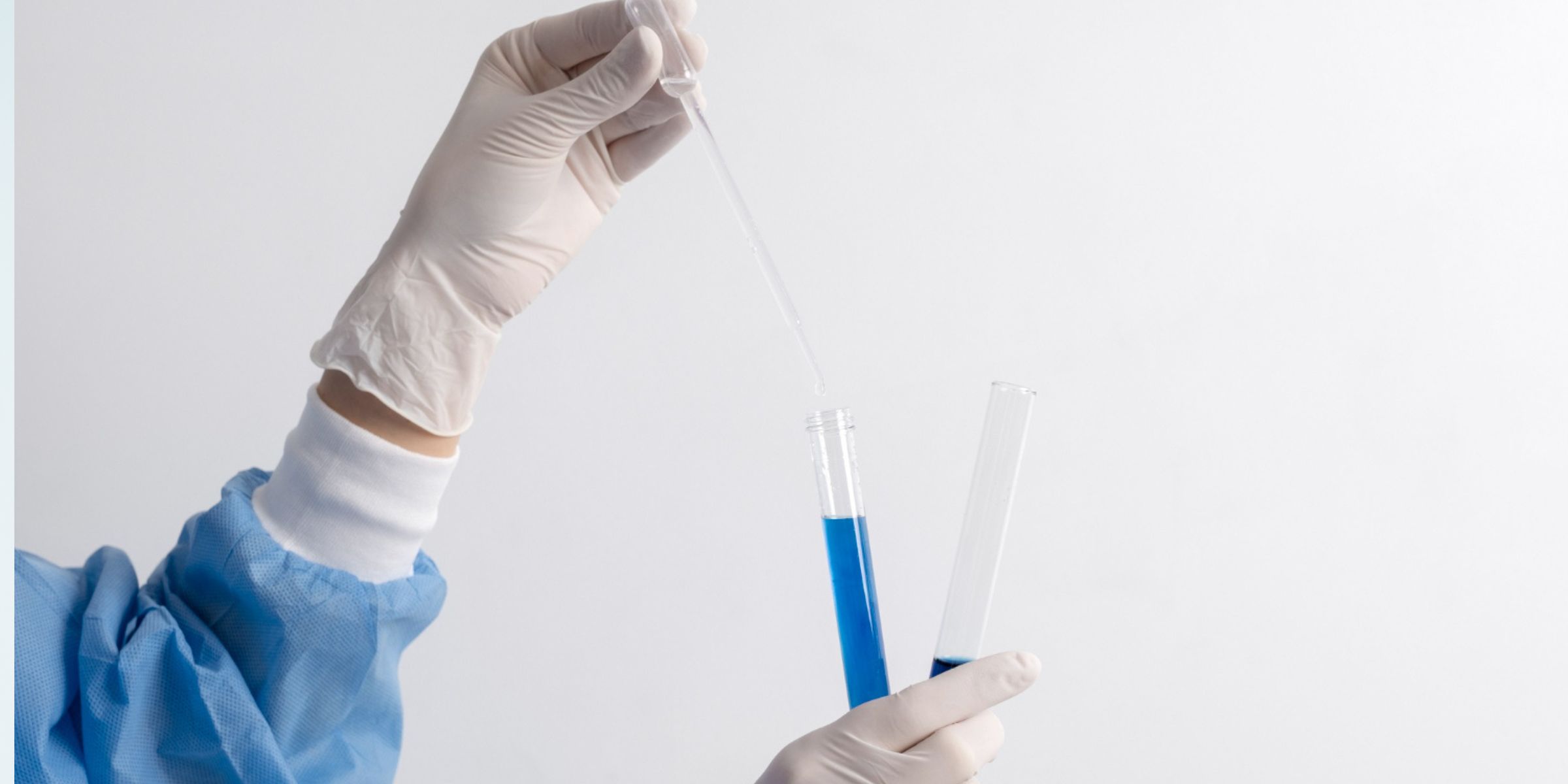 A lab technician transferring blue liquid between test tubes using a dropper | Source: Freepik