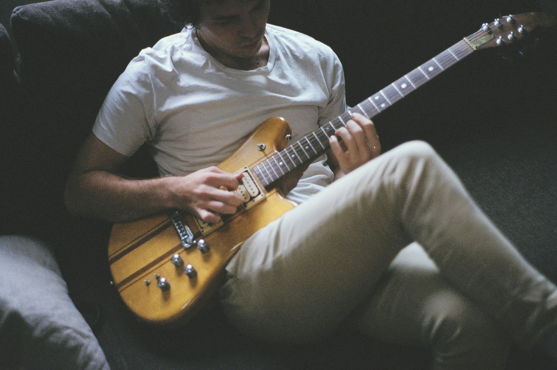 A man playing an electric guitar on a sofa | Source: Unsplash
