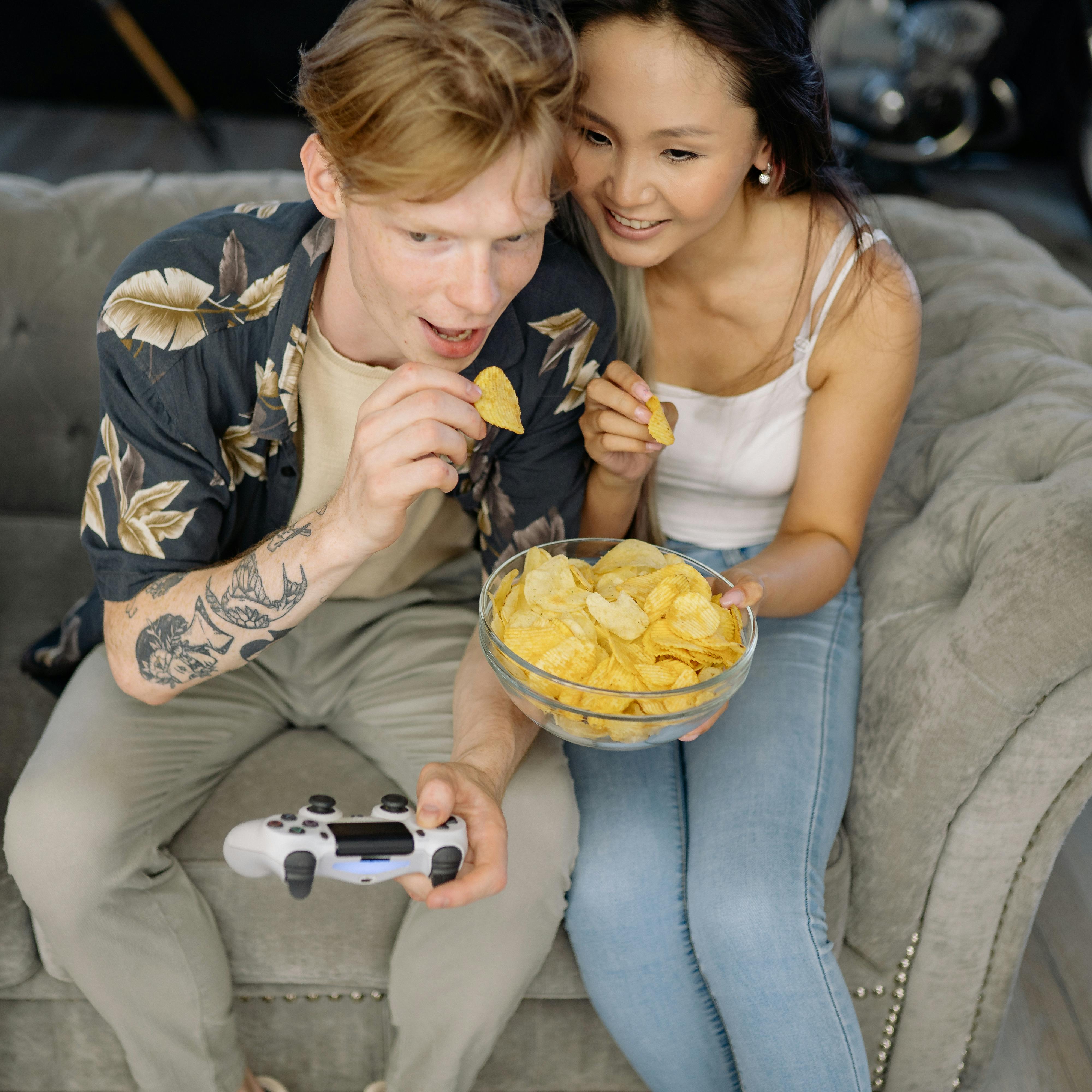A couple sharing snacks while gaming | Source: Pexels