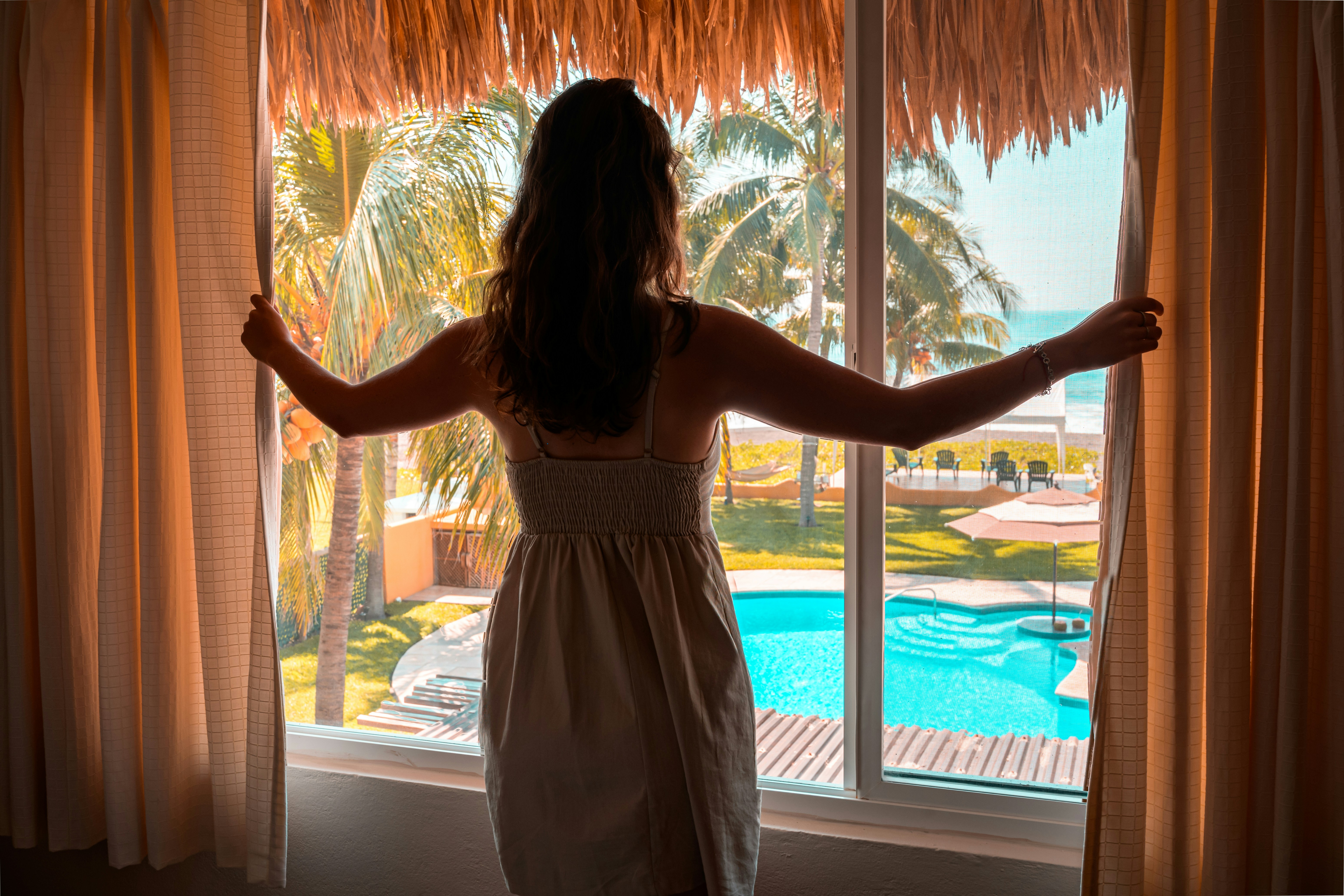 Uma pessoa em pé na janela de um quarto de hotel | Fonte: Unsplash