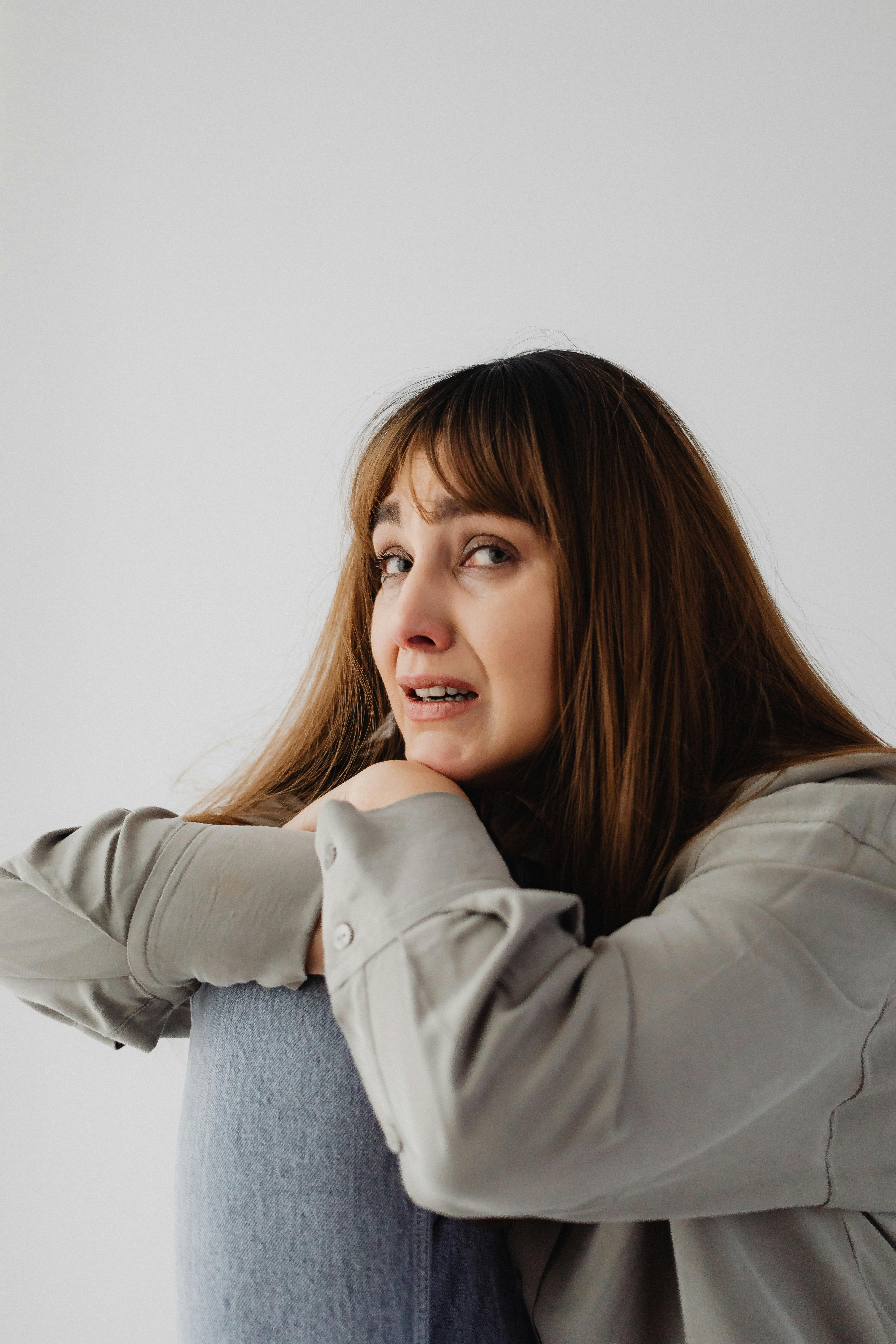 An emotional woman leaning against a chair | Source: Pexels