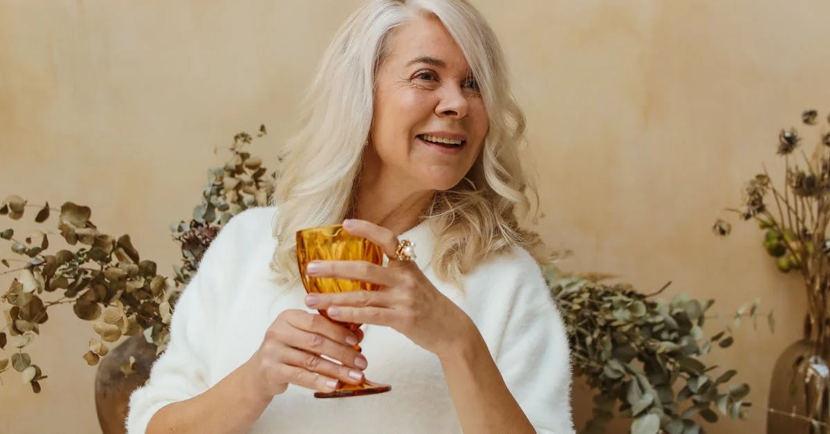 A senior woman holding a goblet and smiling | Source: Pexels