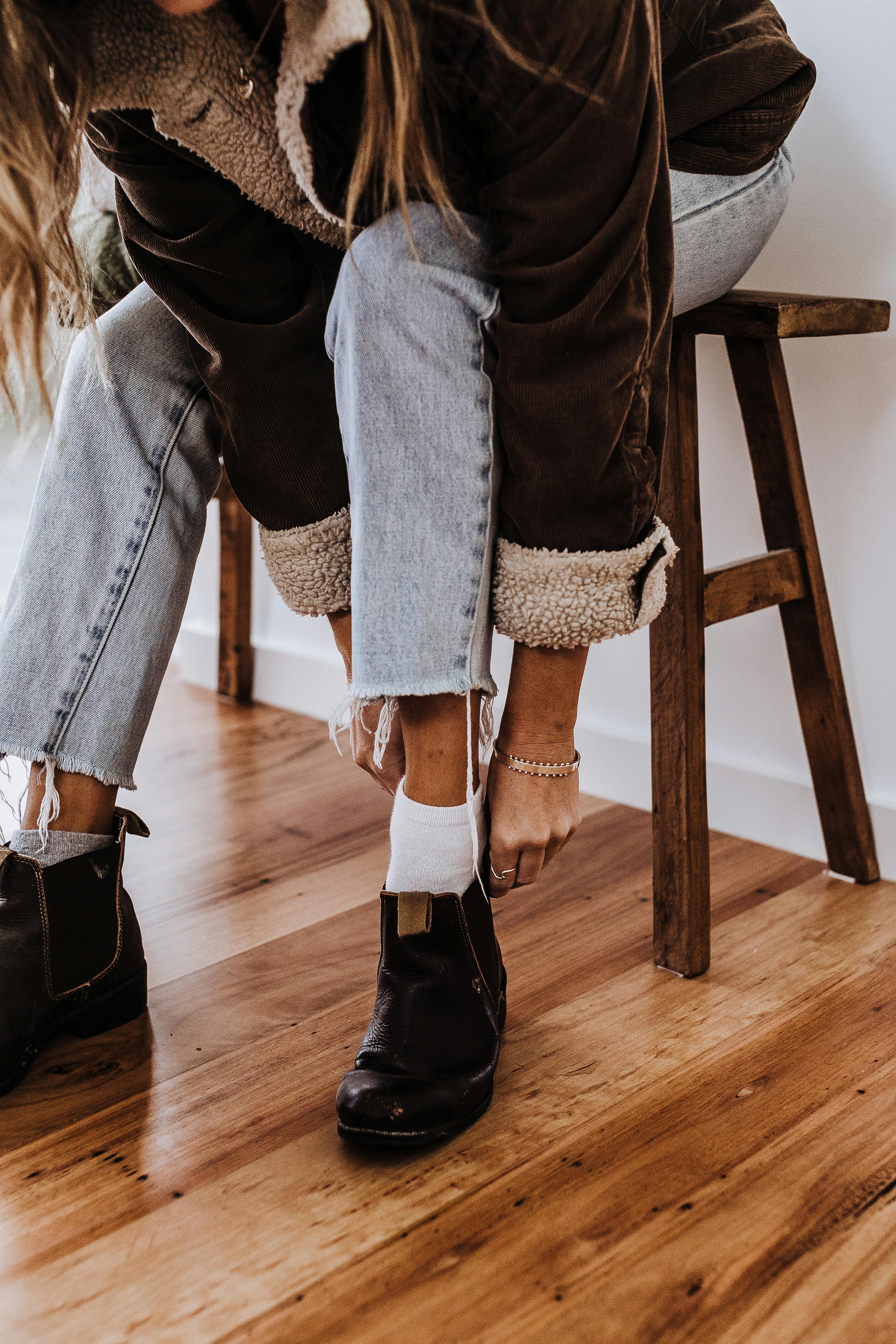 A woman putting on a pair of boots | Source: Pexels