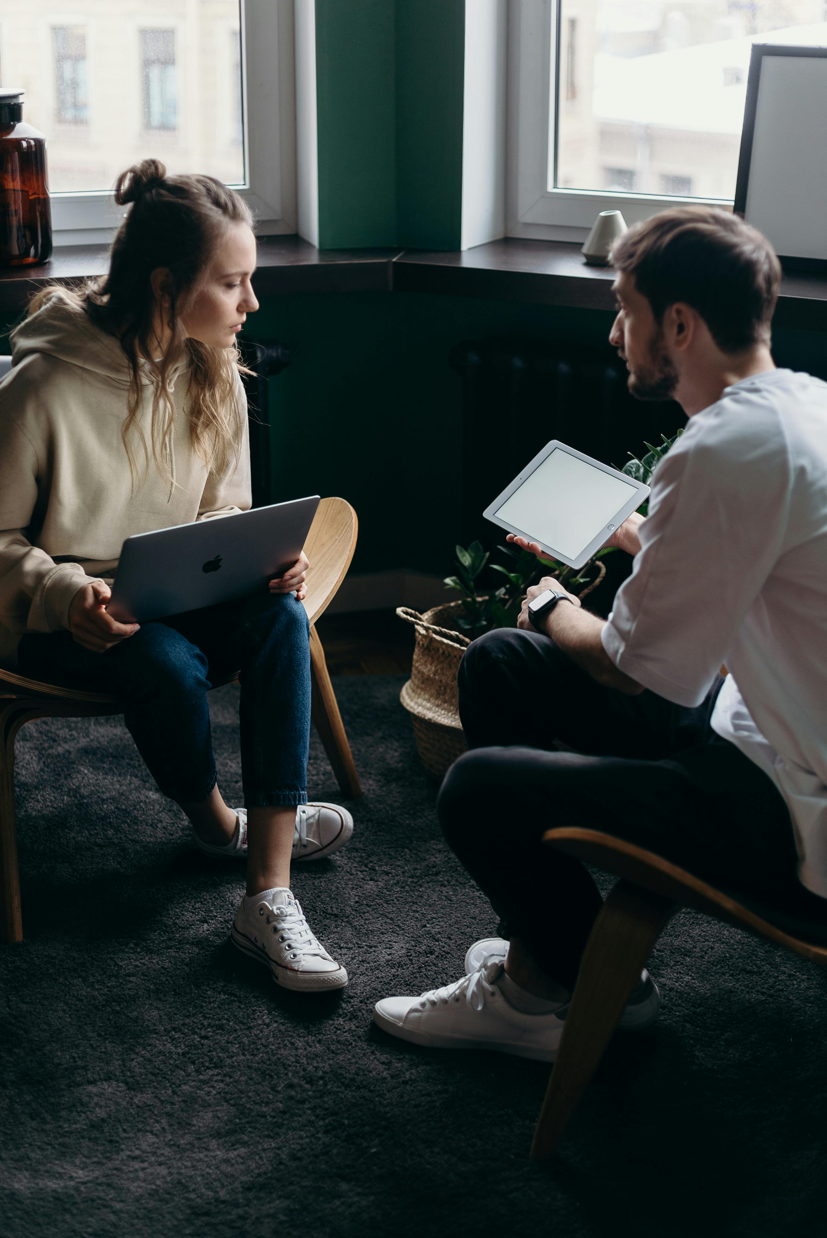 A man and a woman talking while holding a laptop and an iPad | Source: Pexels