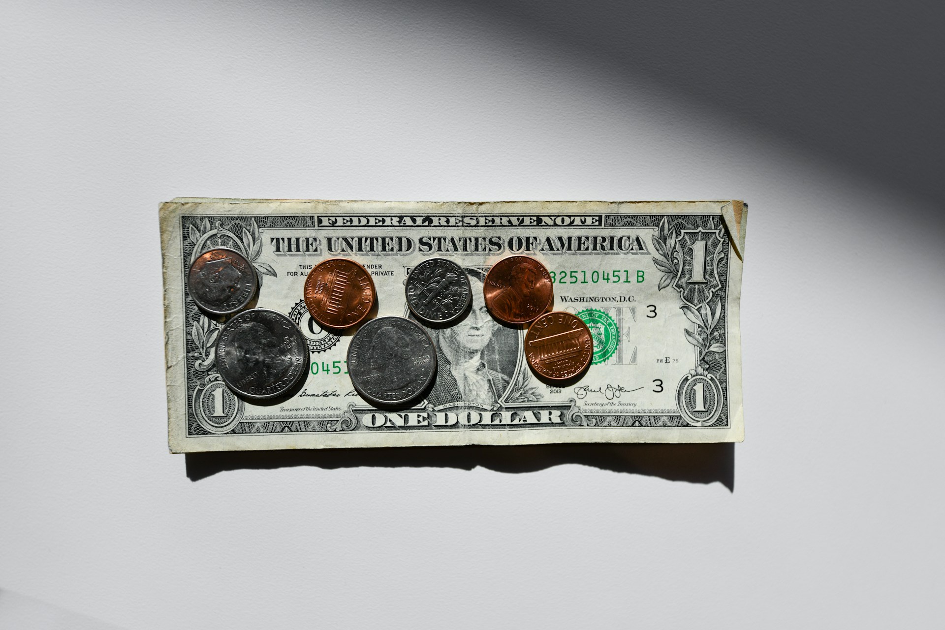 Coins on top of a thin stack of dollar bills | Source: Unsplash