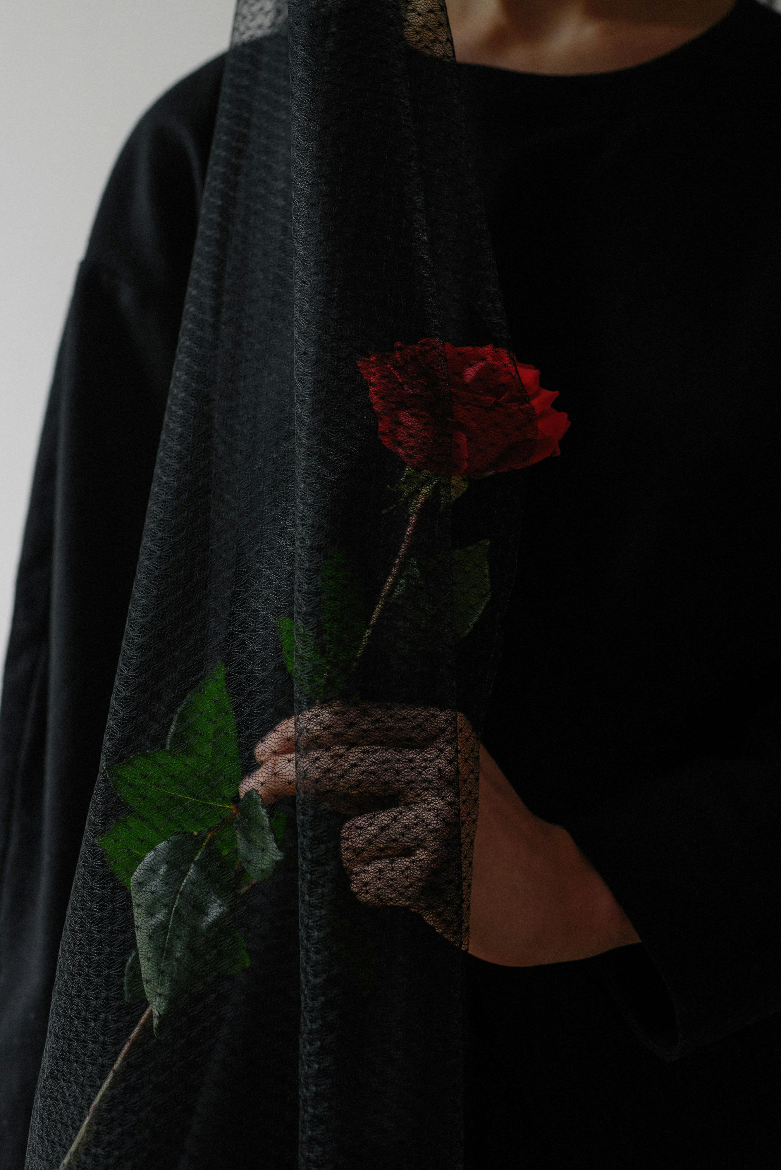 A woman dressed in black holding a red rose | Source: Pexels