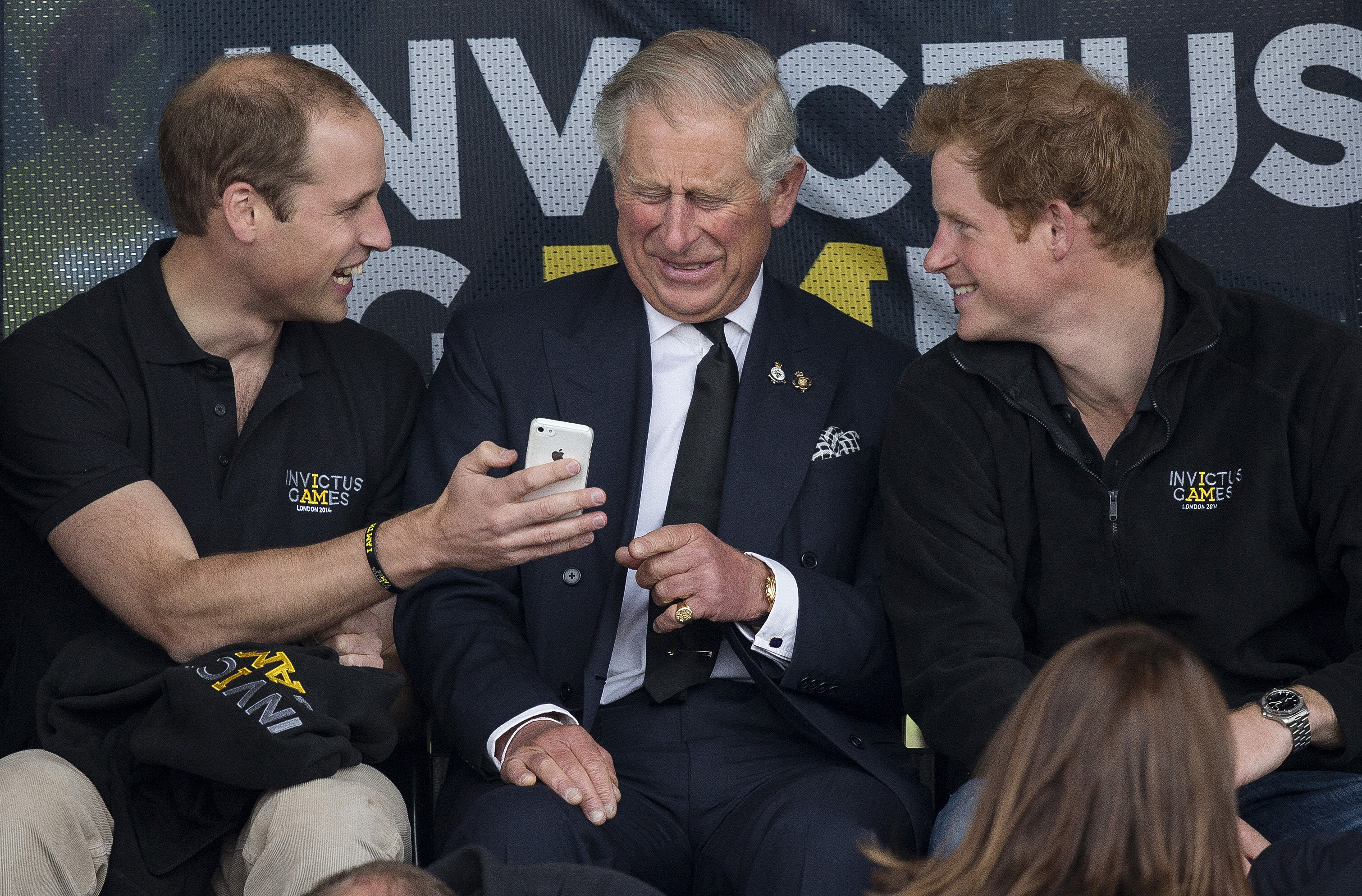 Prince William, Prince Charles and Prince Harry laugh at an image on a mobile phone whilst watching Day One of the Invictus Games at Lee Valley Athletics Stadium in Edmonton on September 11, 2014 | Source: Getty Images
