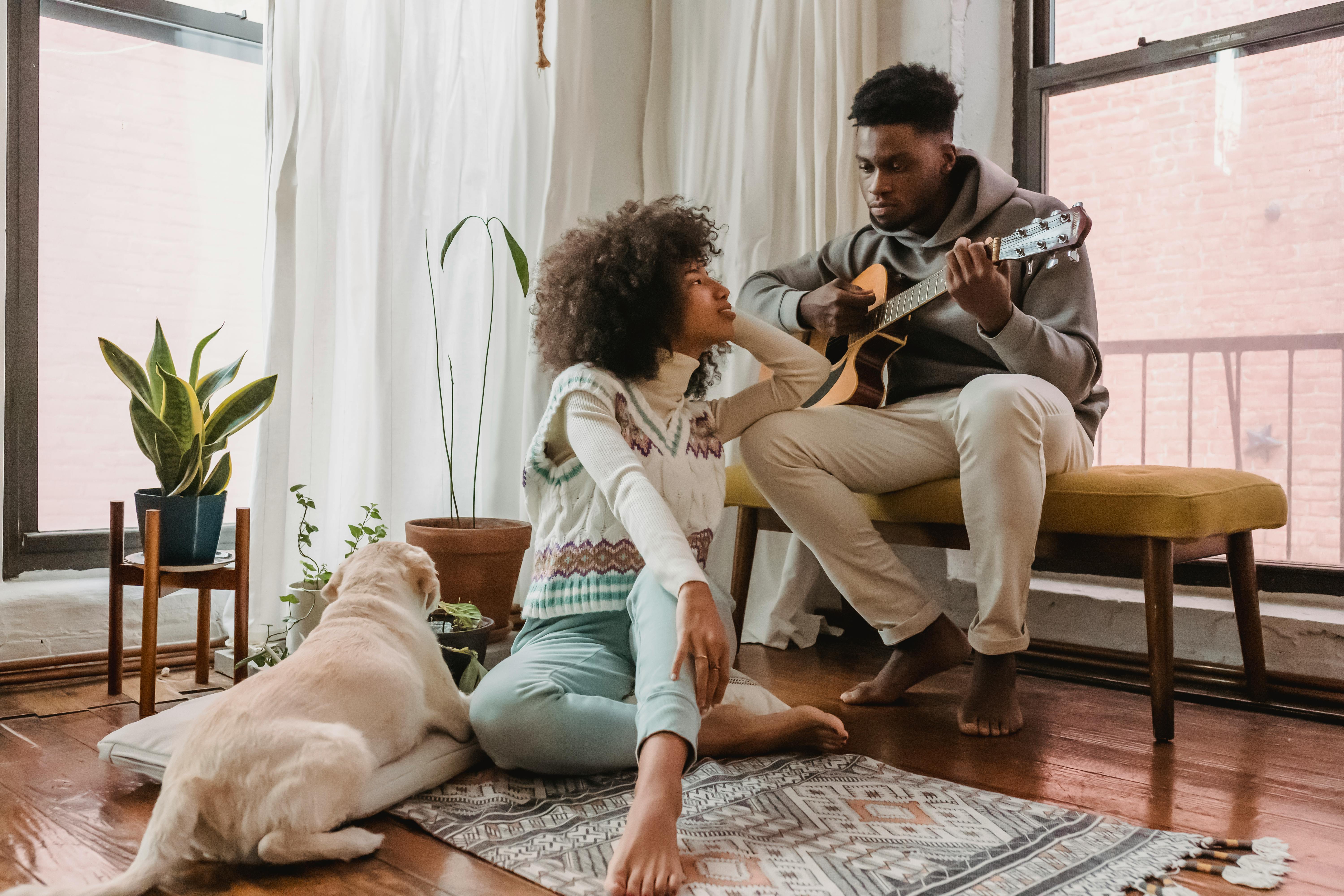A woman watching a man play the guitar | Source: Pexels