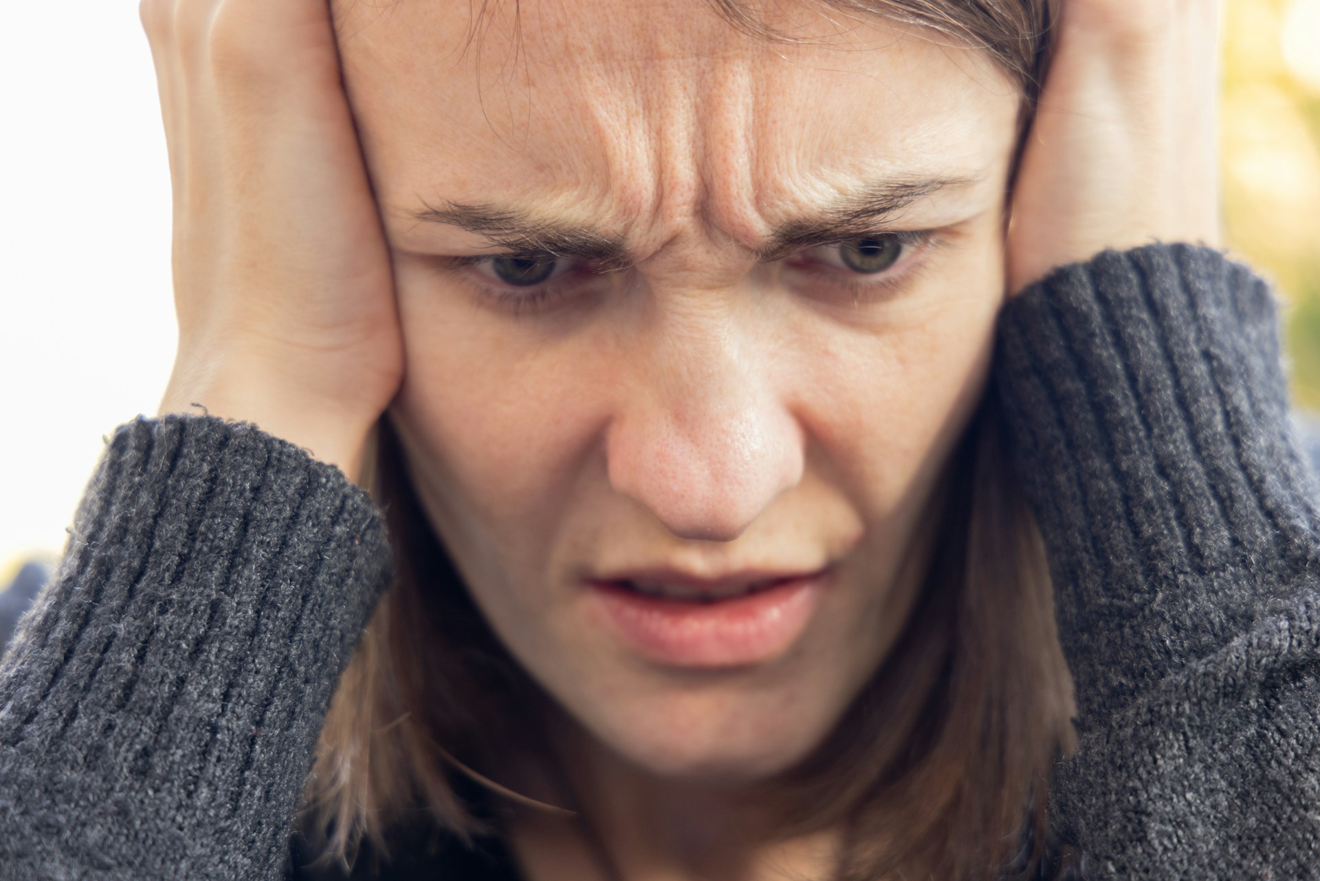 A woman resting her head in her hands while frowning | Source: Unsplash