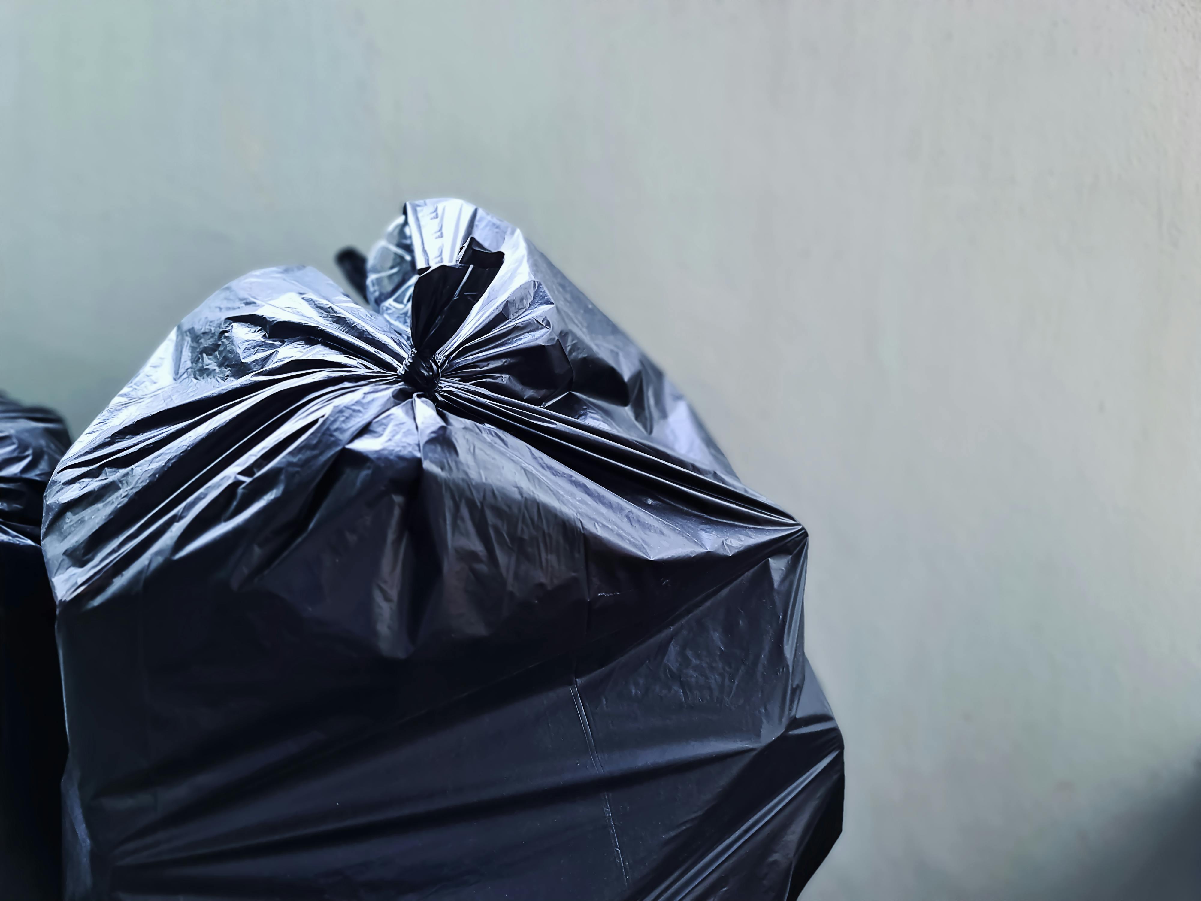 Saco plástico preto perto de muro de concreto | Fonte: Pexels