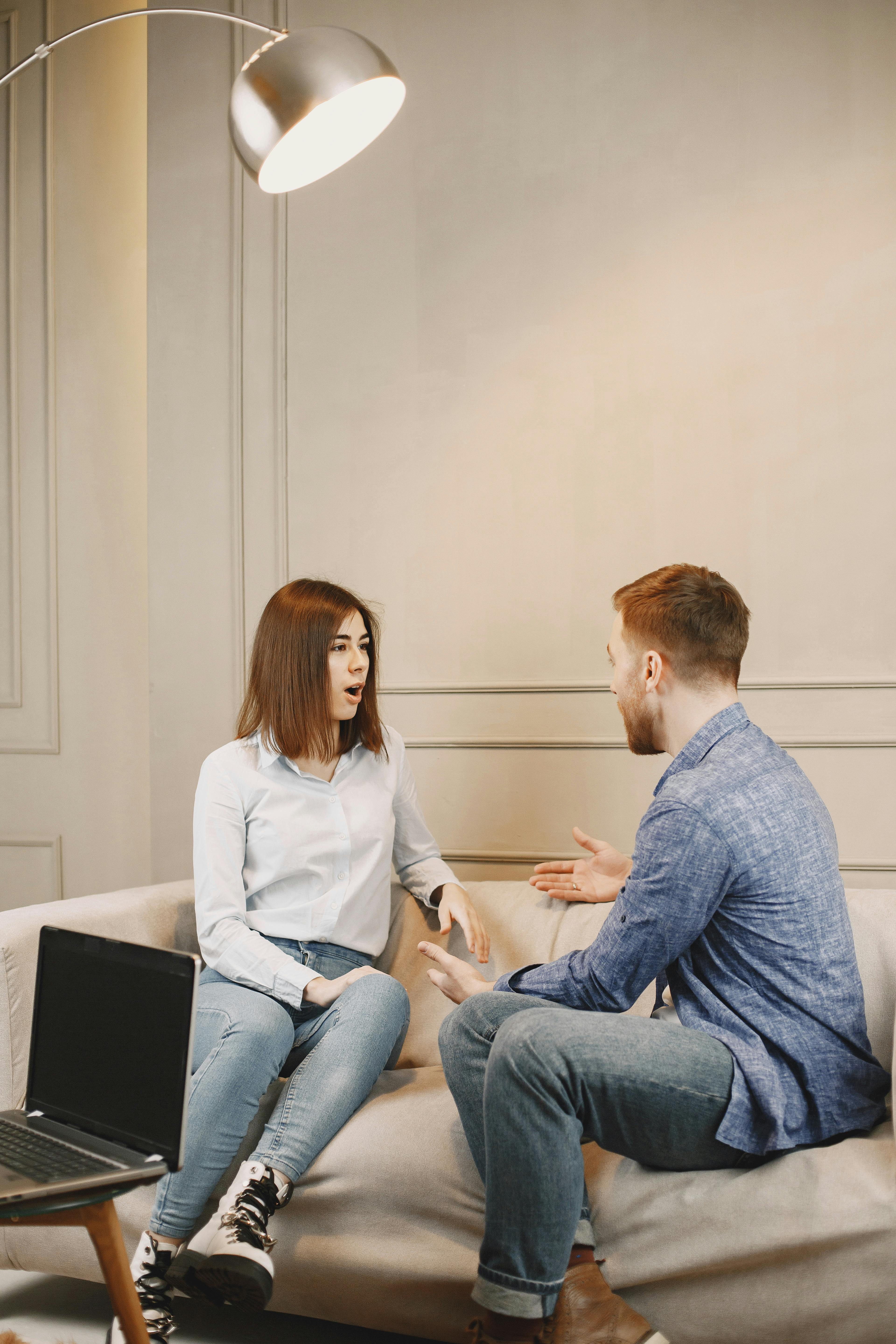 A man and a woman talking while sitting on a couch | Source: Pexels