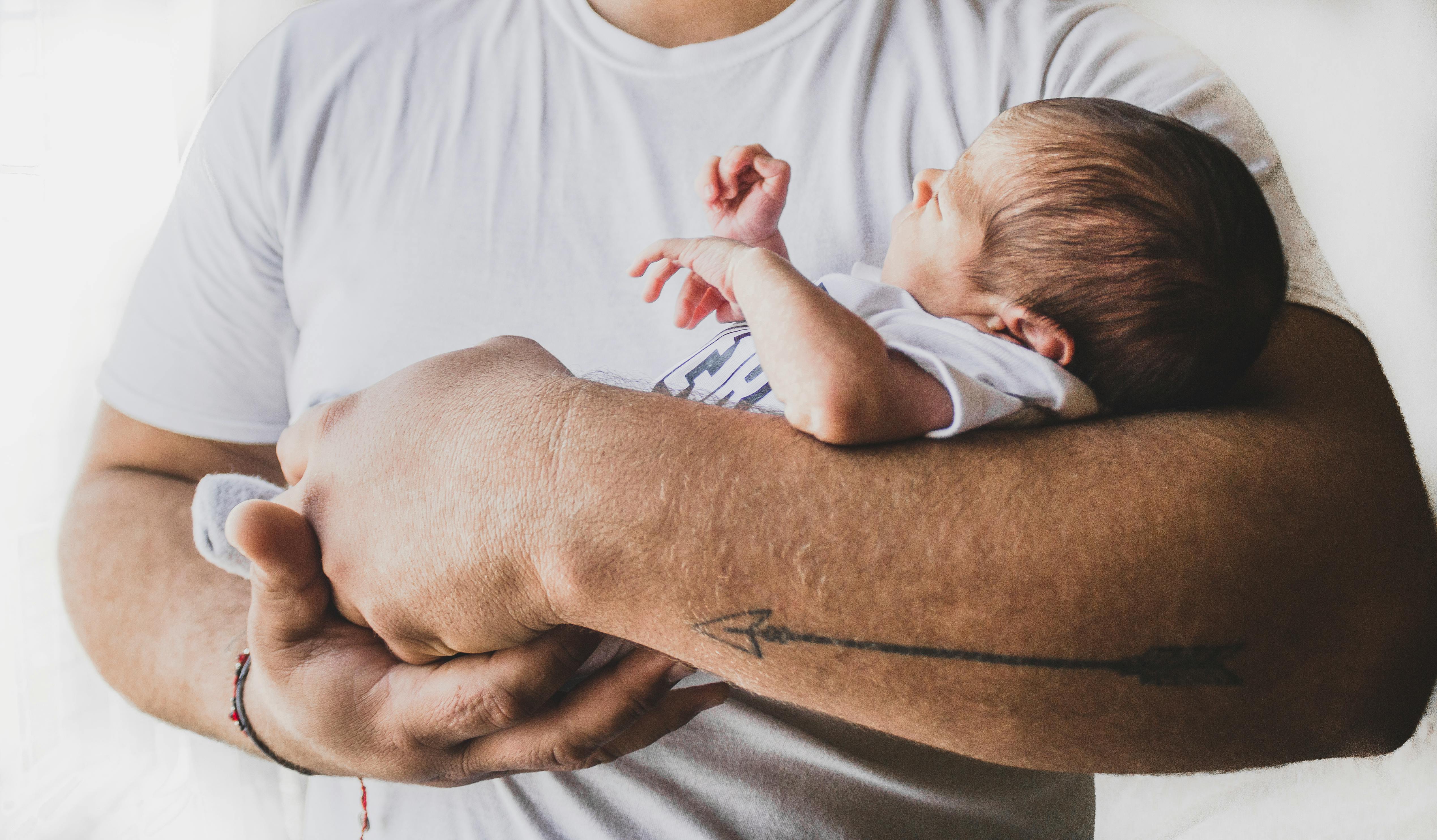 Man holding a newborn baby in his arms | Source: Pexels