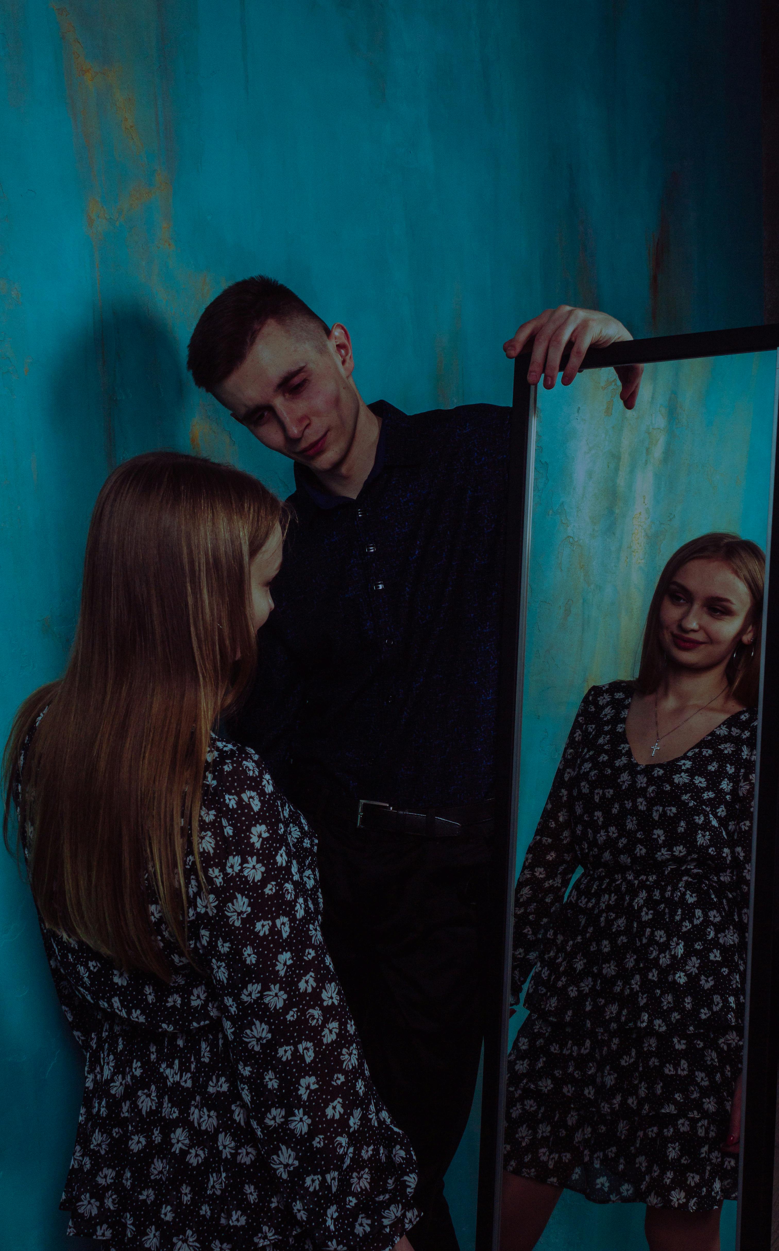 Man staring as a woman looks at herself in the mirror | Source: Pexels