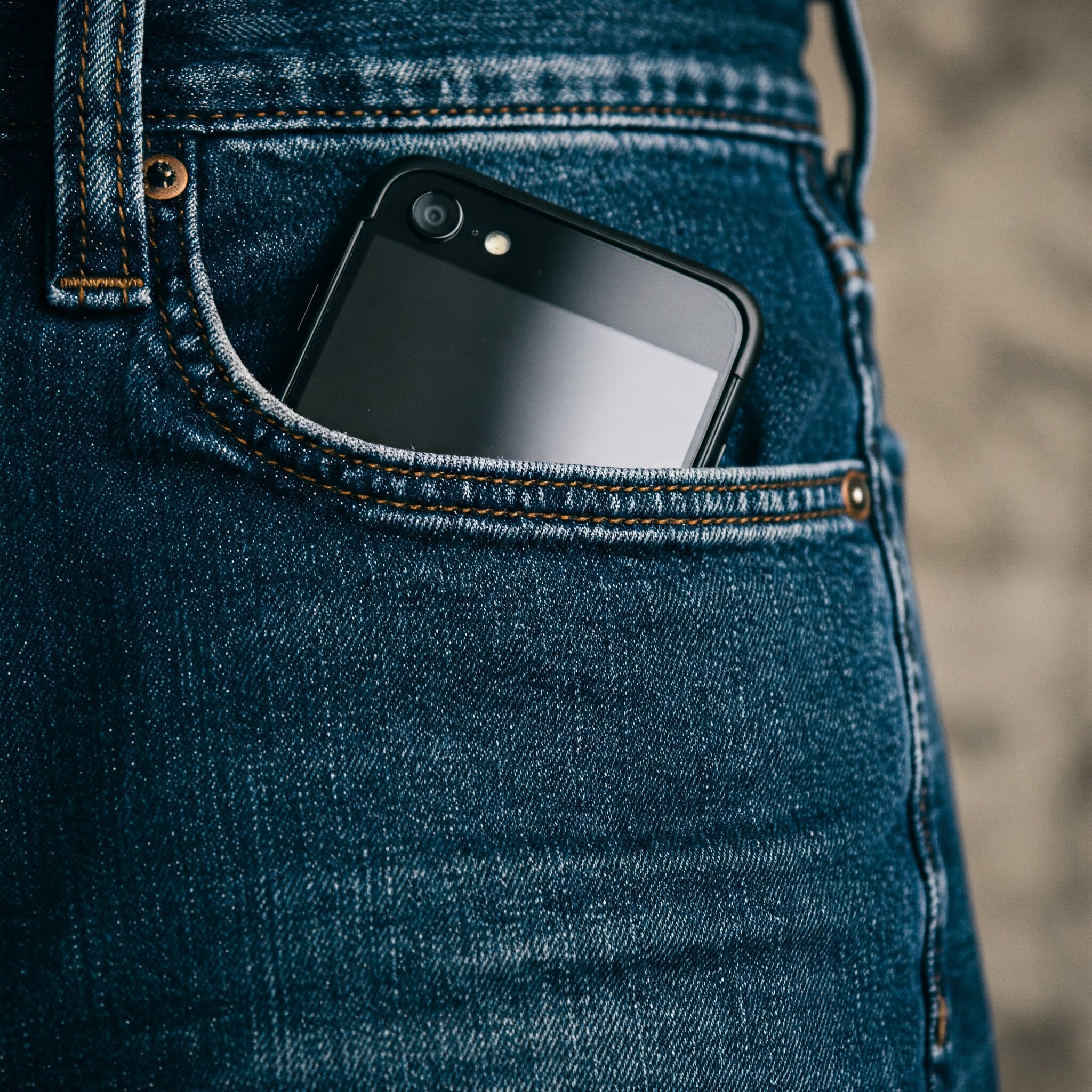 Um celular no bolso de uma calça jeans masculina | Fonte: Gemini