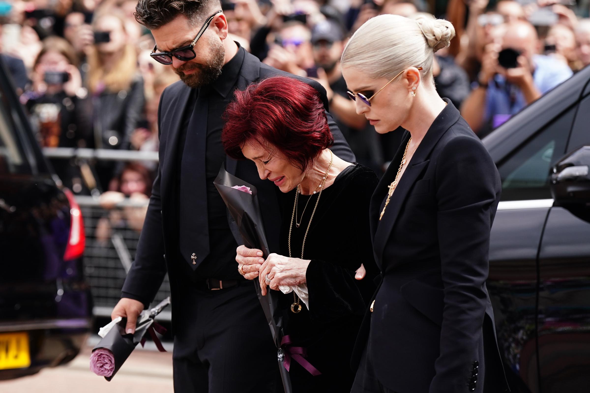 (L-R) Jack Osbourne, Sharon Osbourne and Kelly Osbourne arrive to view tributes to the late Ozzy Osbourne from fans as his funeral cortege travels through his home city of Birmingham on July 30, 2025, in Birmingham, England. | Source: Getty Images