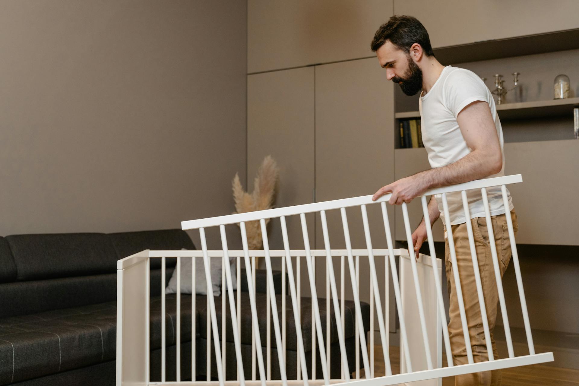 Man holding pieces of a dismantled baby crib | Source: Pexels