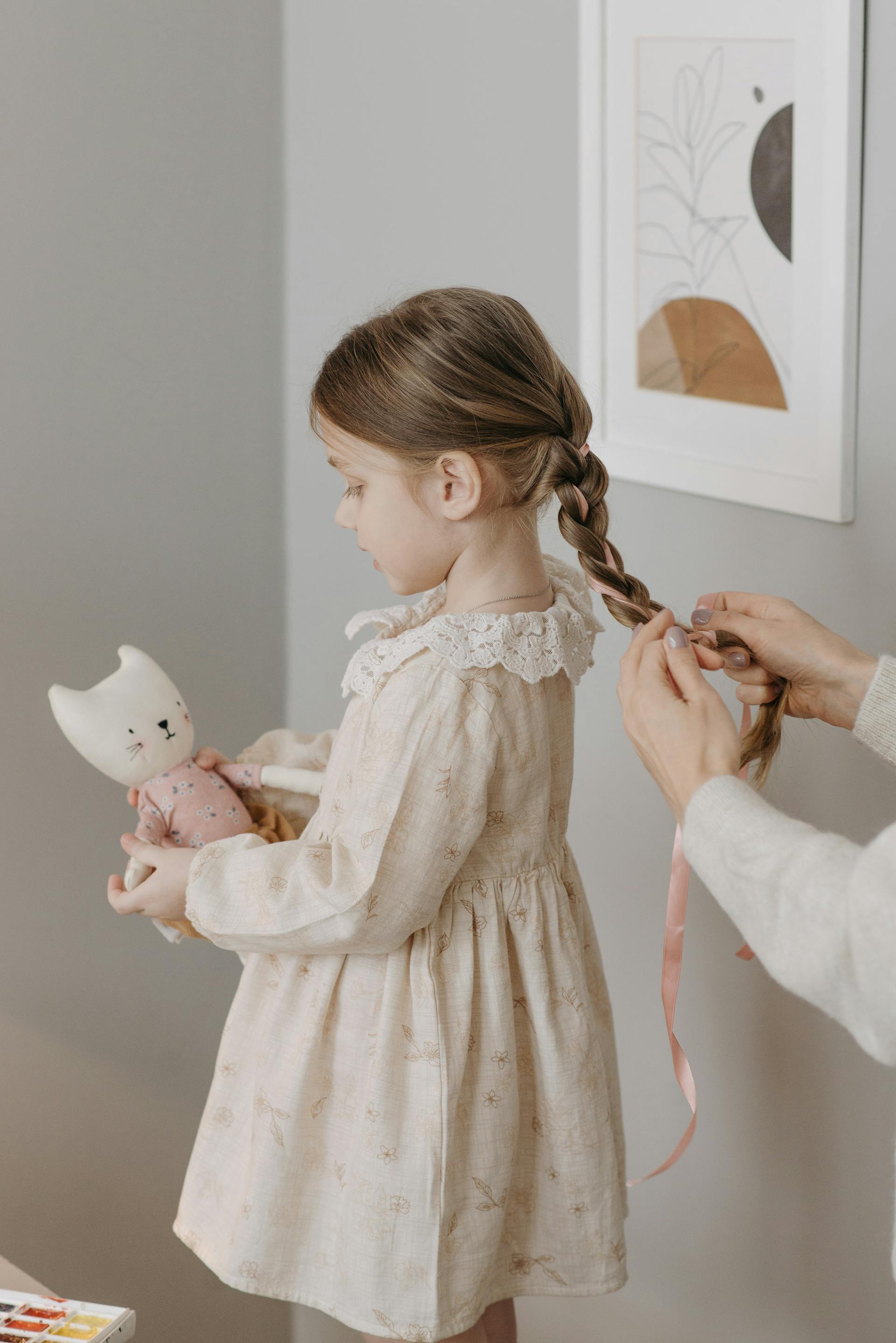 A woman braiding her daughter's hair | Source: Pexels