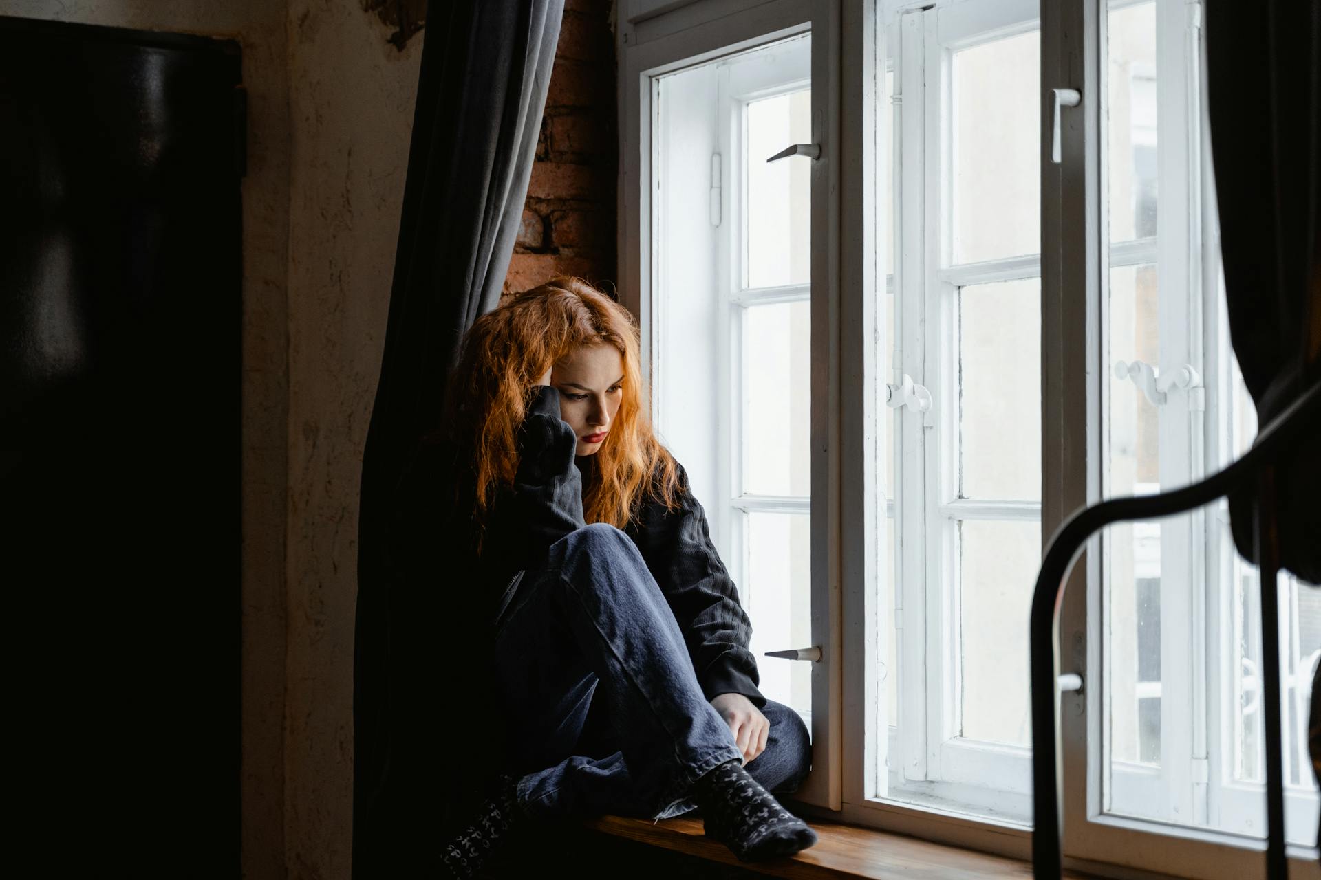 A woman sitting near a window | Source: Pexels