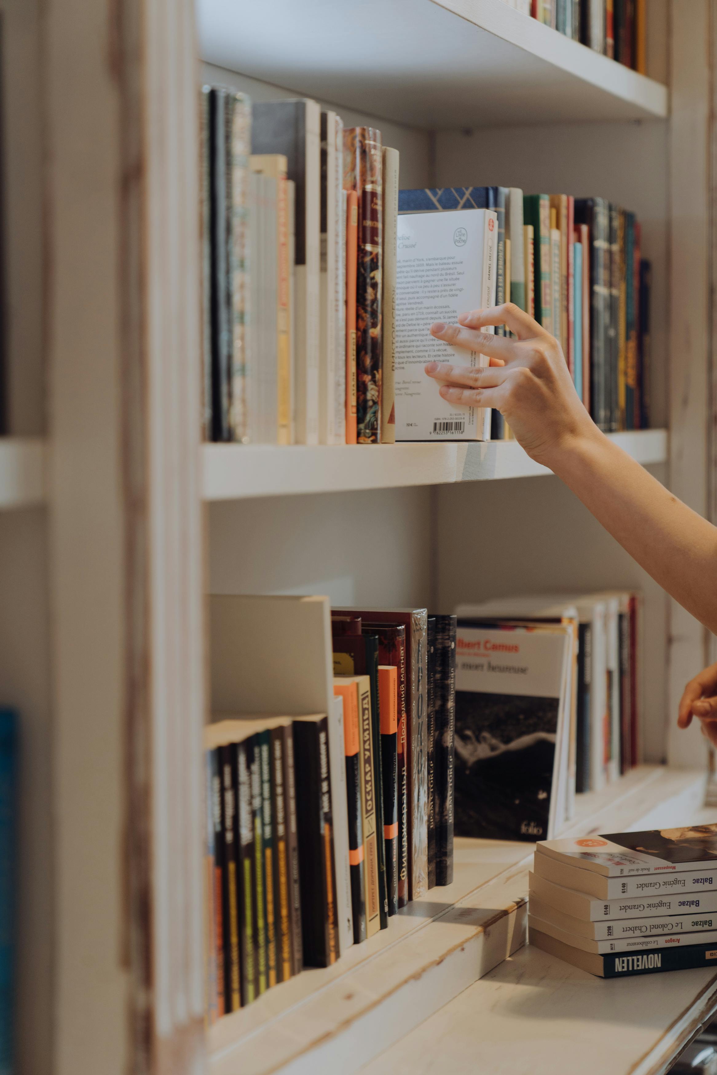 A person reaching for a book in a library | Source: Pexels