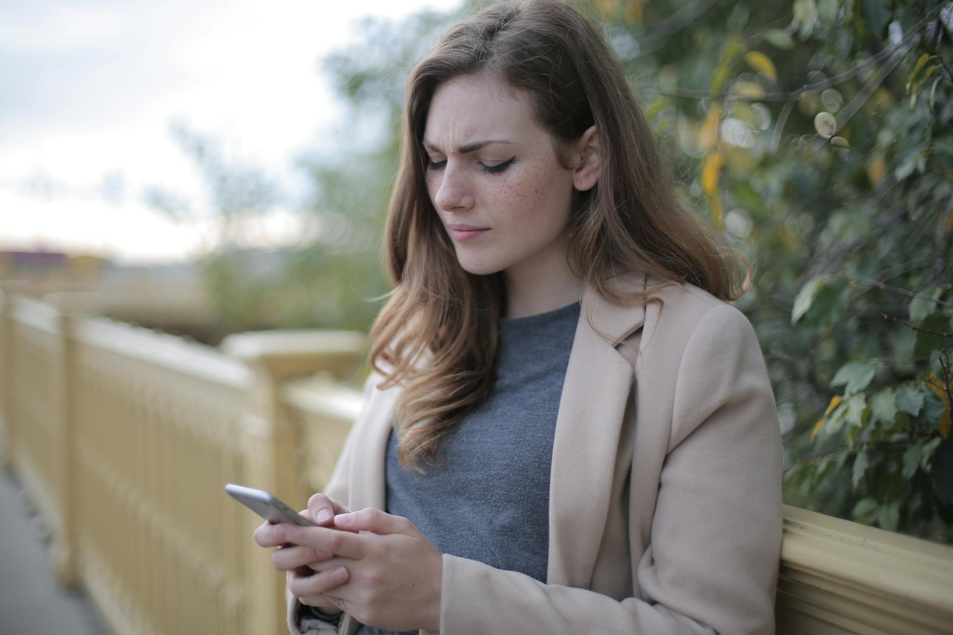A woman frowning while looking at her phone | Source: Pexels