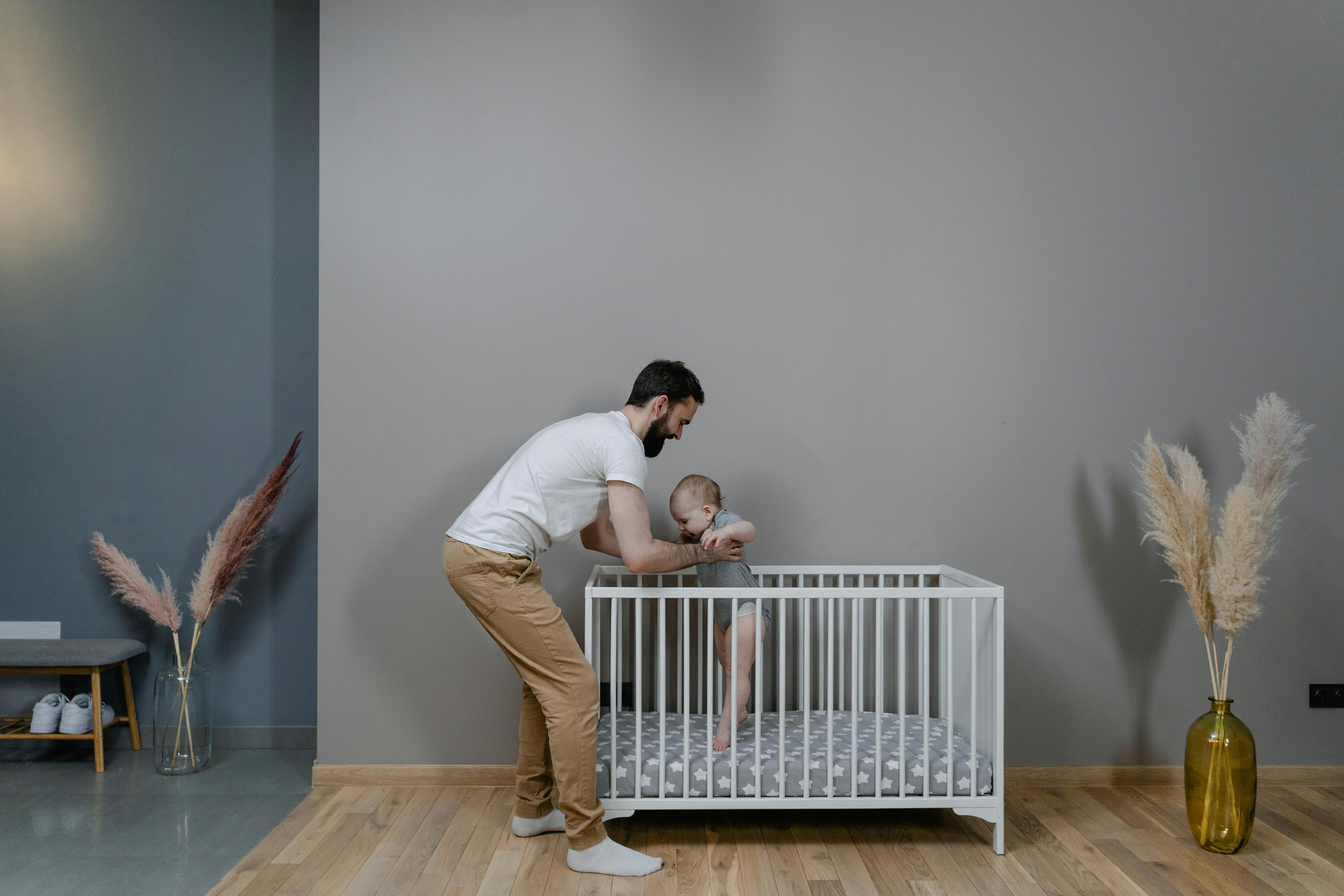 A man holding a baby in a crib | Source: Pexels