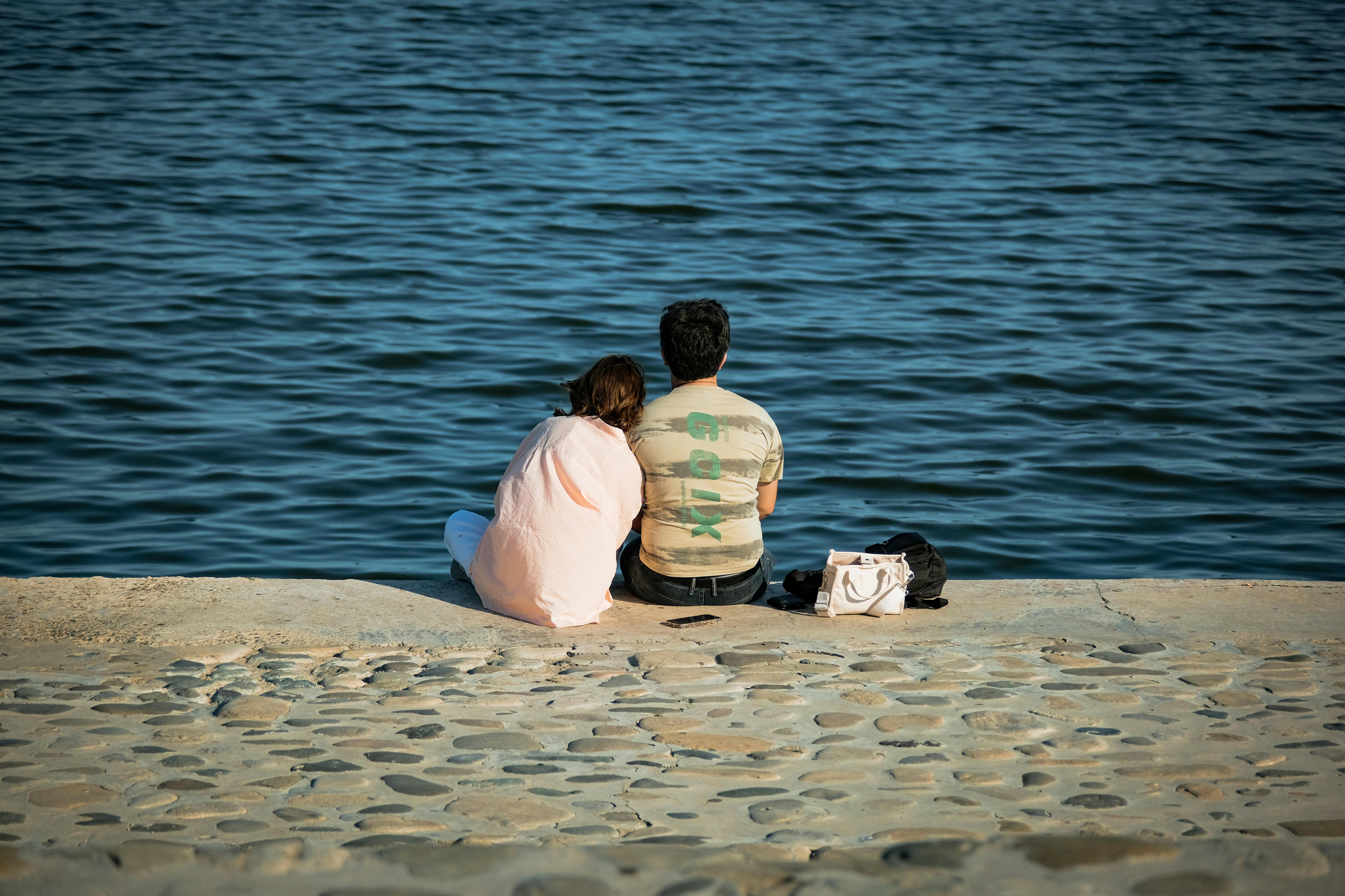 Couple sitting by the serene waterfront | Source: Pexels
