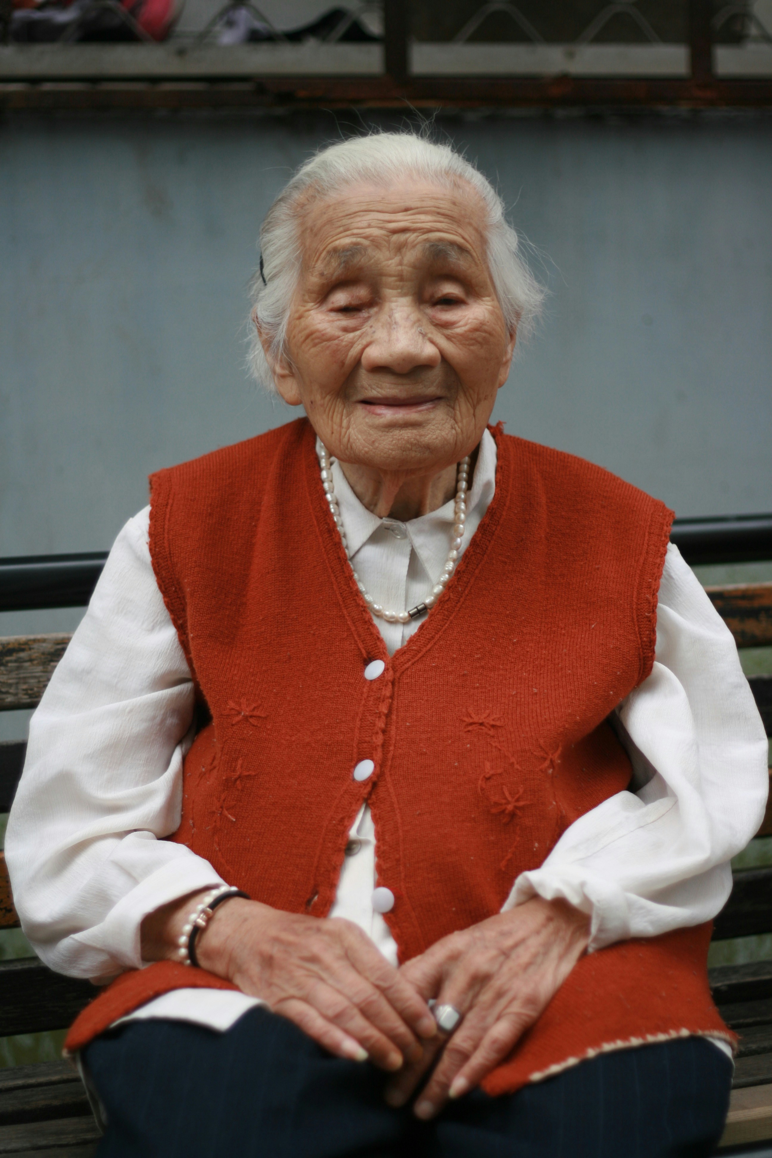 An old woman wearing a red vest | Source: Unsplash