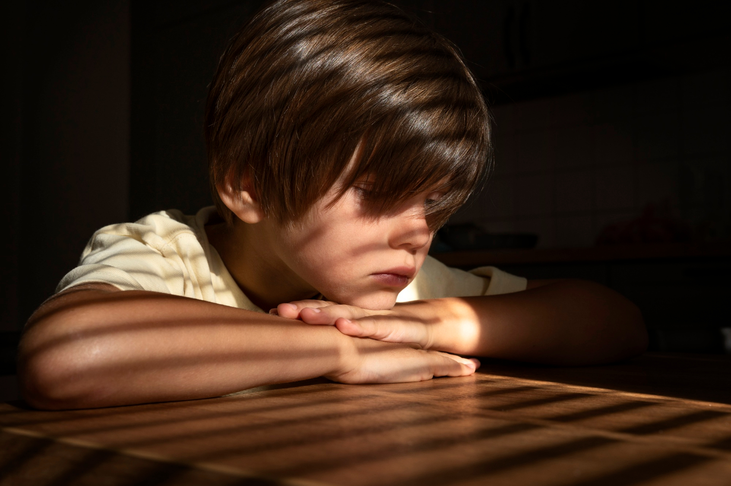 A sad boy seated at a table | Source: Freepik