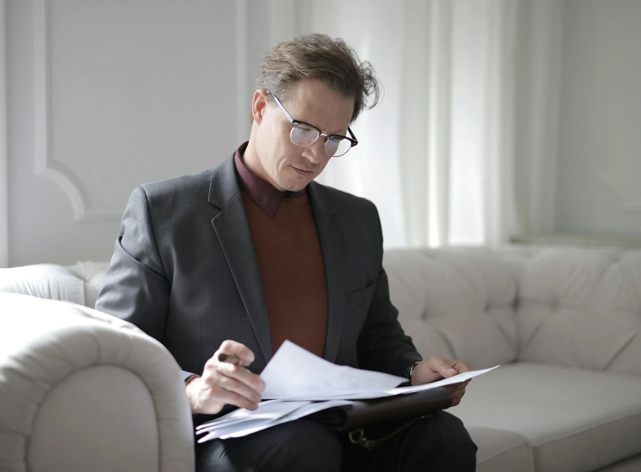 A man reading documents on a couch | Source: Pexels