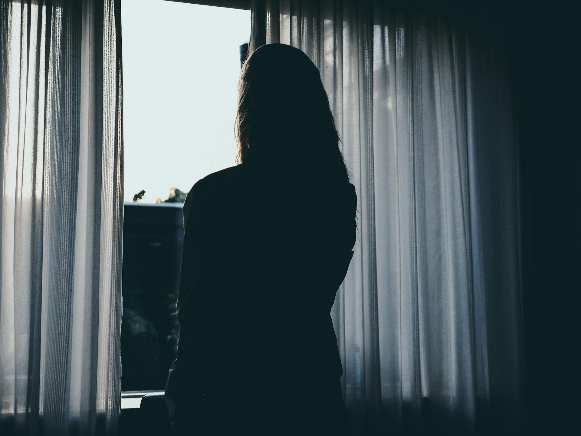 A woman standing near the window | Source: Pexels