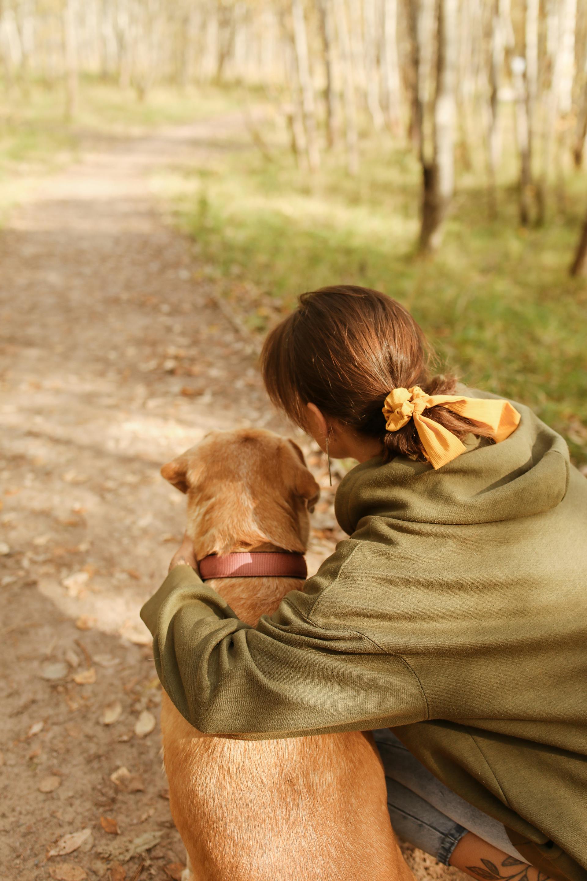 A back-view of a woman kneeling beside her dog | Source: Pexels