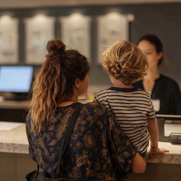 A woman and a child speaking to a receptionist | Source: Midjourney