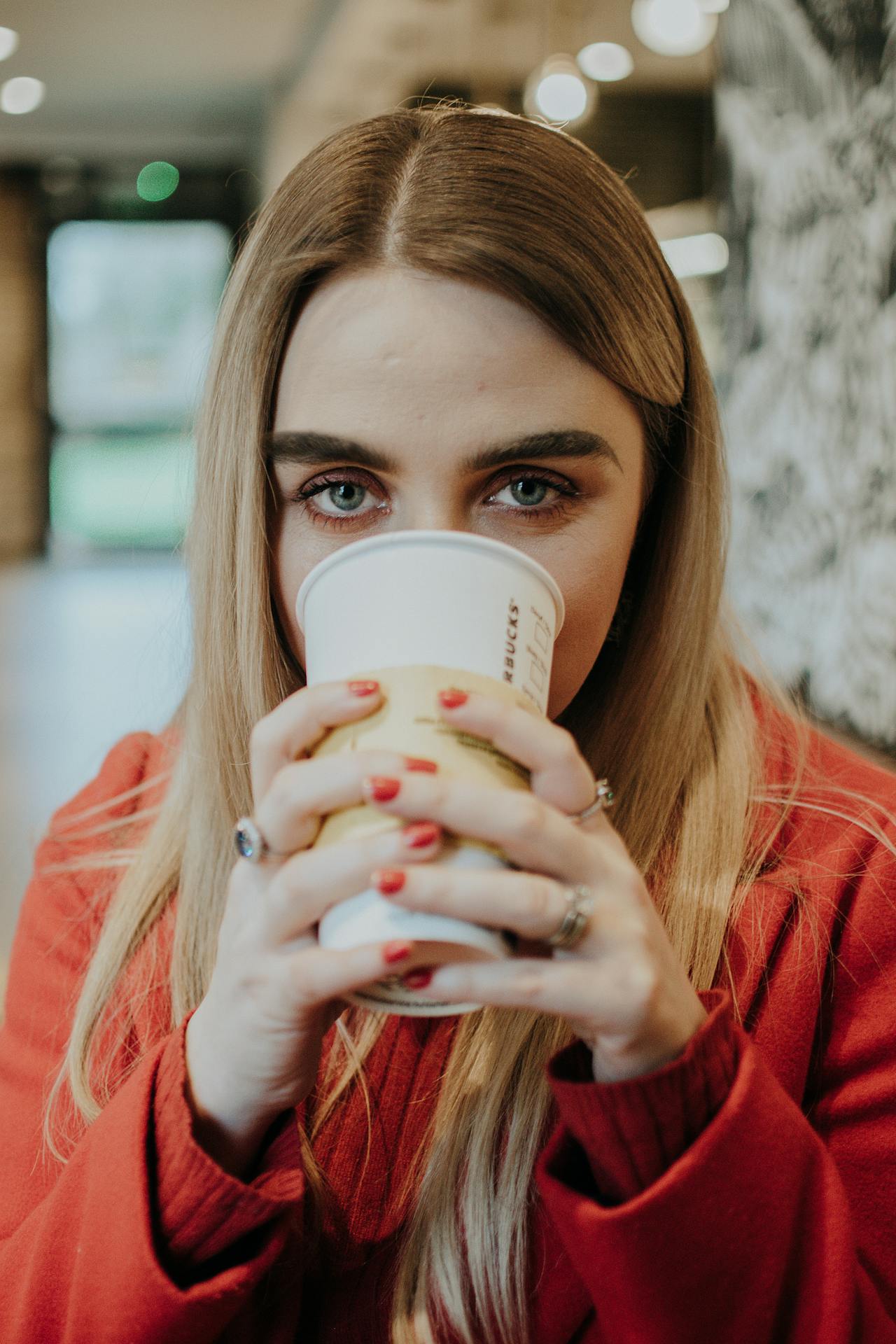 A woman drinking from a disposable cup while staring curiously | Source: Pexels