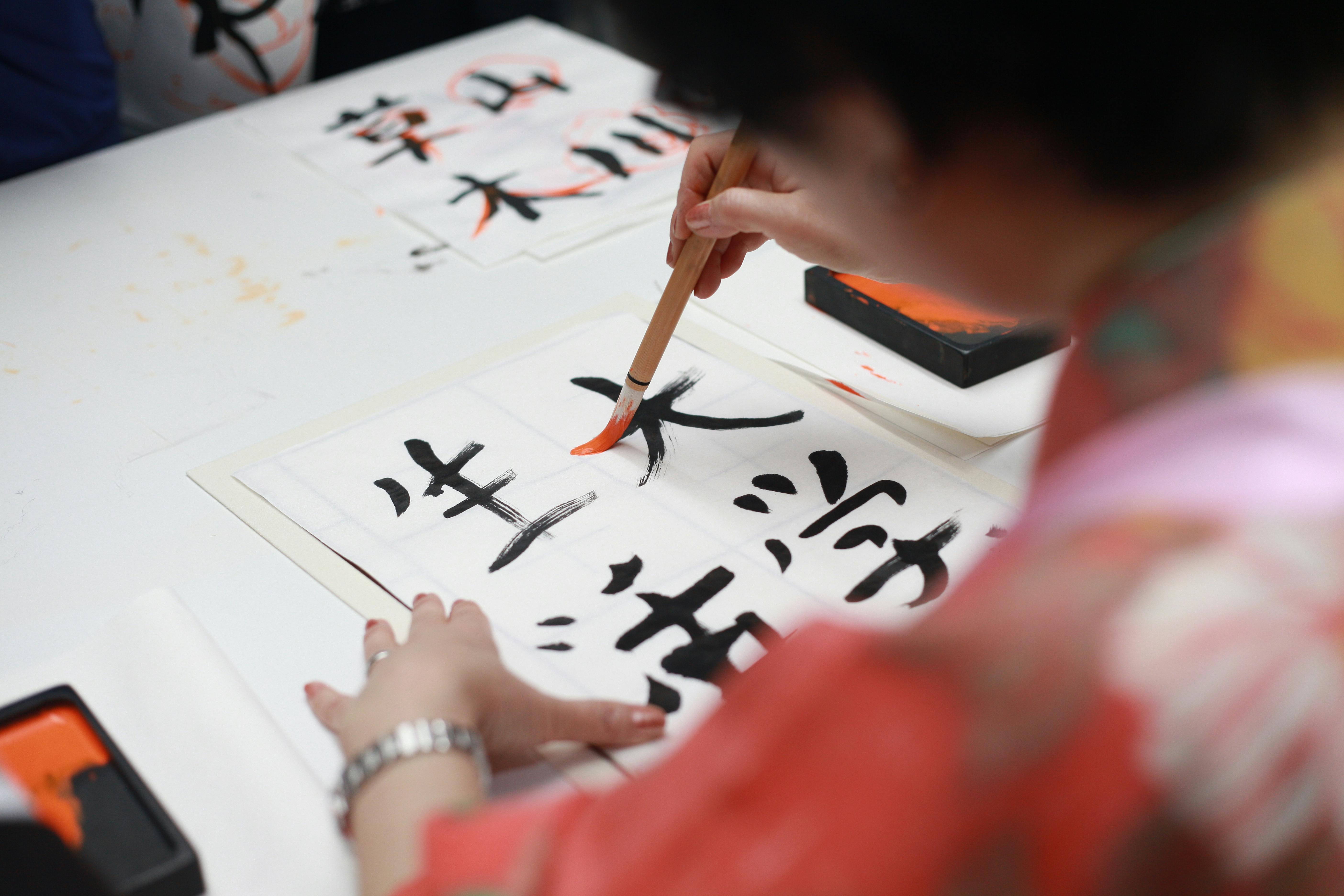 A person holding a brush and drawing Kanji script | Source: Pexels