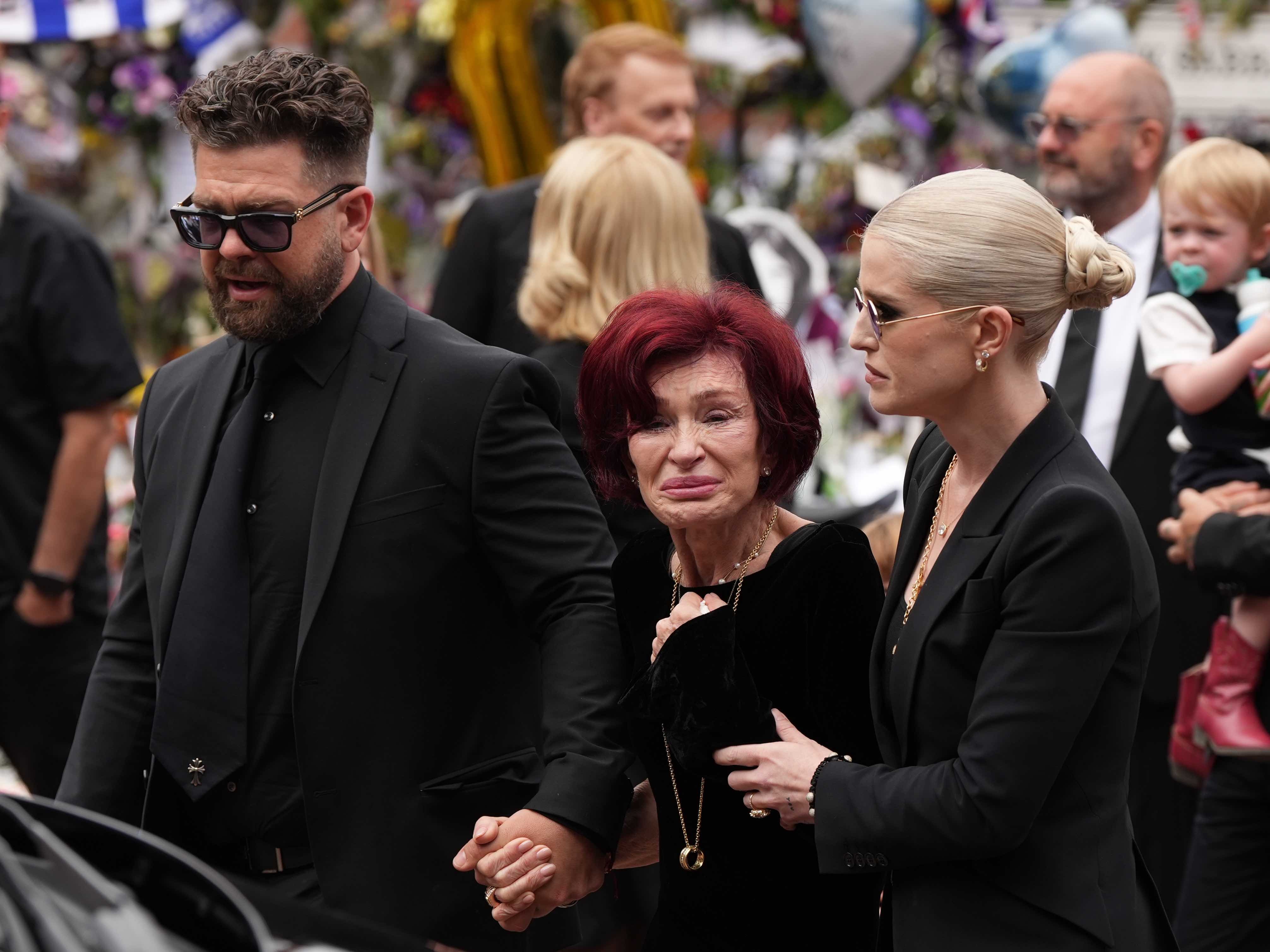 (L-R) Jack Osbourne, Sharon Osbourne and Kelly Osbourne arrive to view tributes to the late Ozzy Osbourne from fans as his funeral cortege travels through his home city of Birmingham on July 30, 2025, in Birmingham, England. | Source: Getty Images