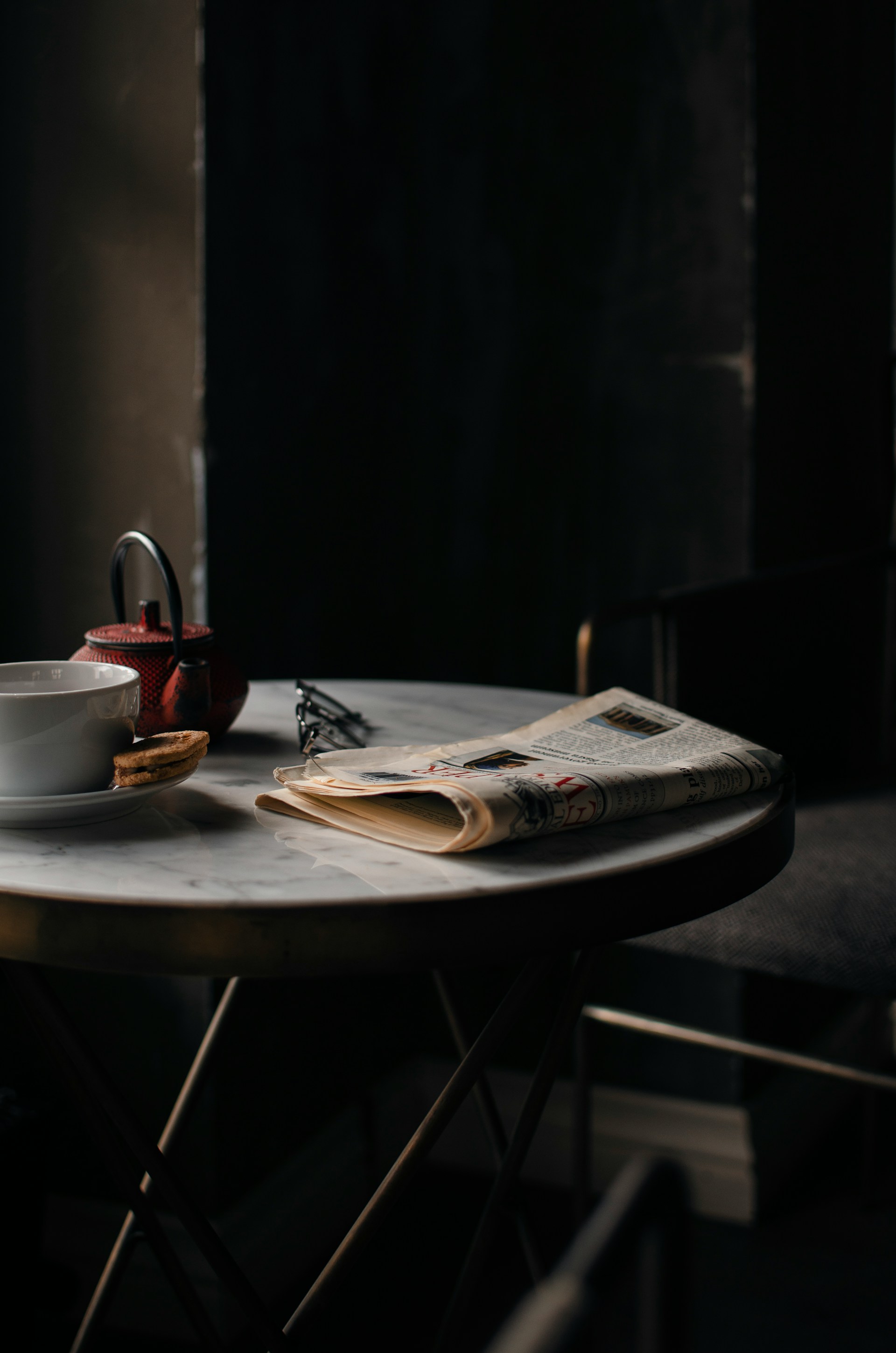 A kettle and coffee cup beside a neatly folded newspaper | Source: Unsplash