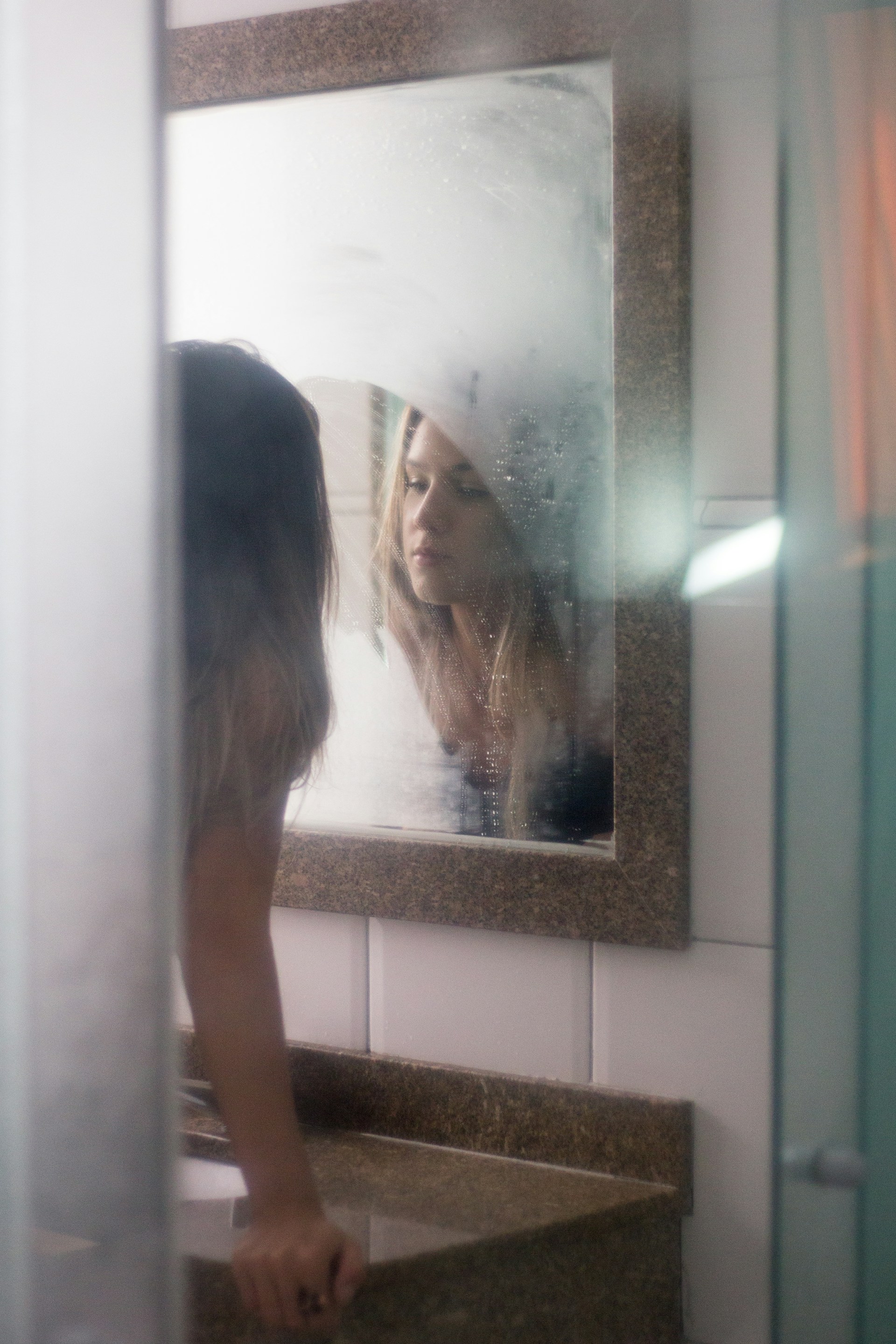 A woman looking at herself in a bathroom mirror | Source: Unsplash