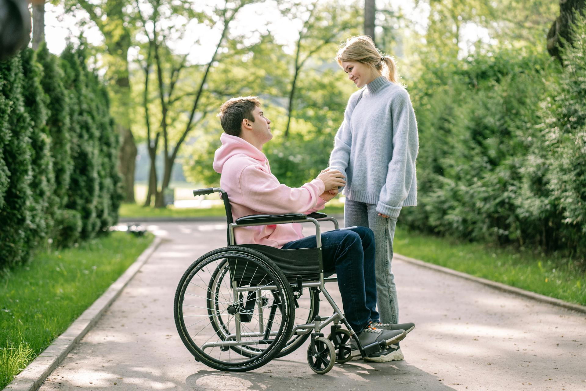 A man in a wheelchair holding a woman's hand | Source: Pexels