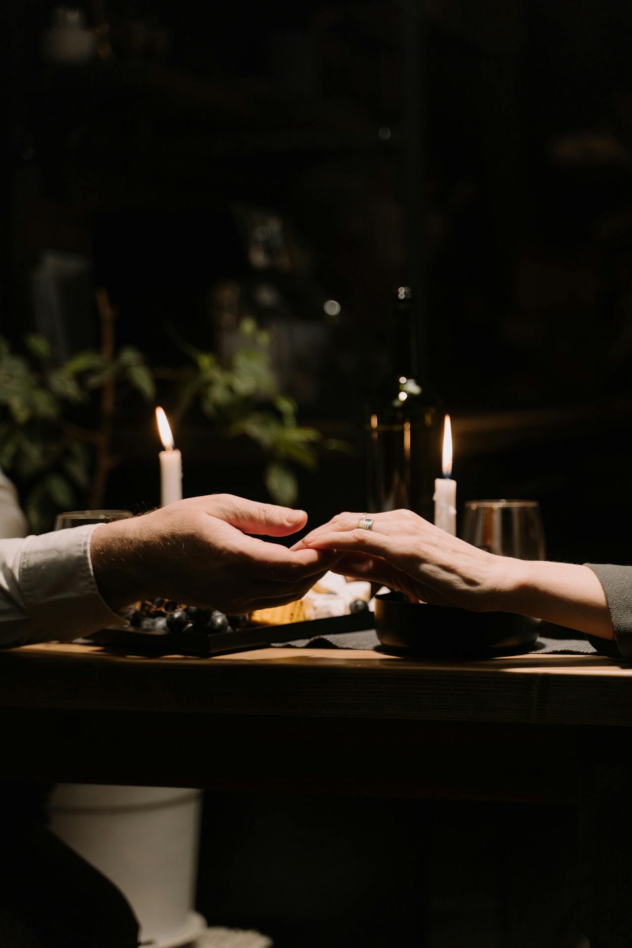 Close-up shot of a couple holding hands against the backdrop of candlelit dinner | Source: Pexels