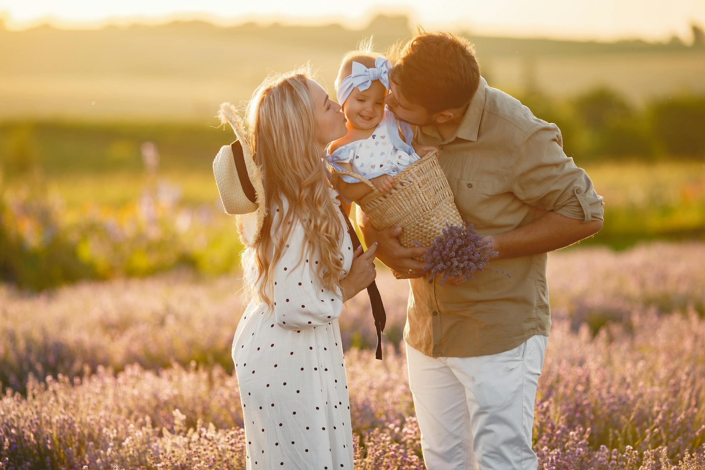 A couple kissing their daughter who is in a basket | Source: Pexels