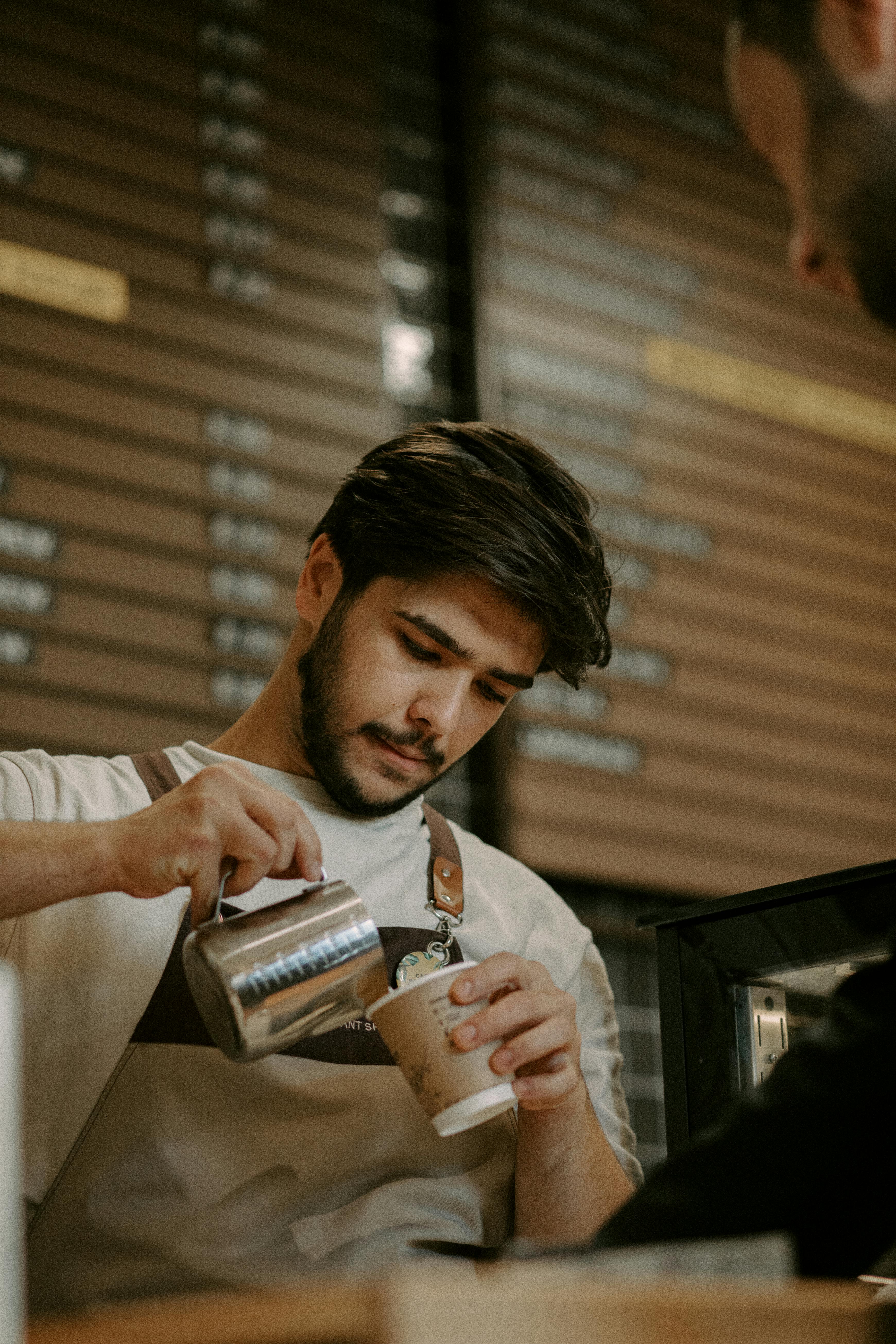 Barista pouring milk into coffee | Source: Pexels
